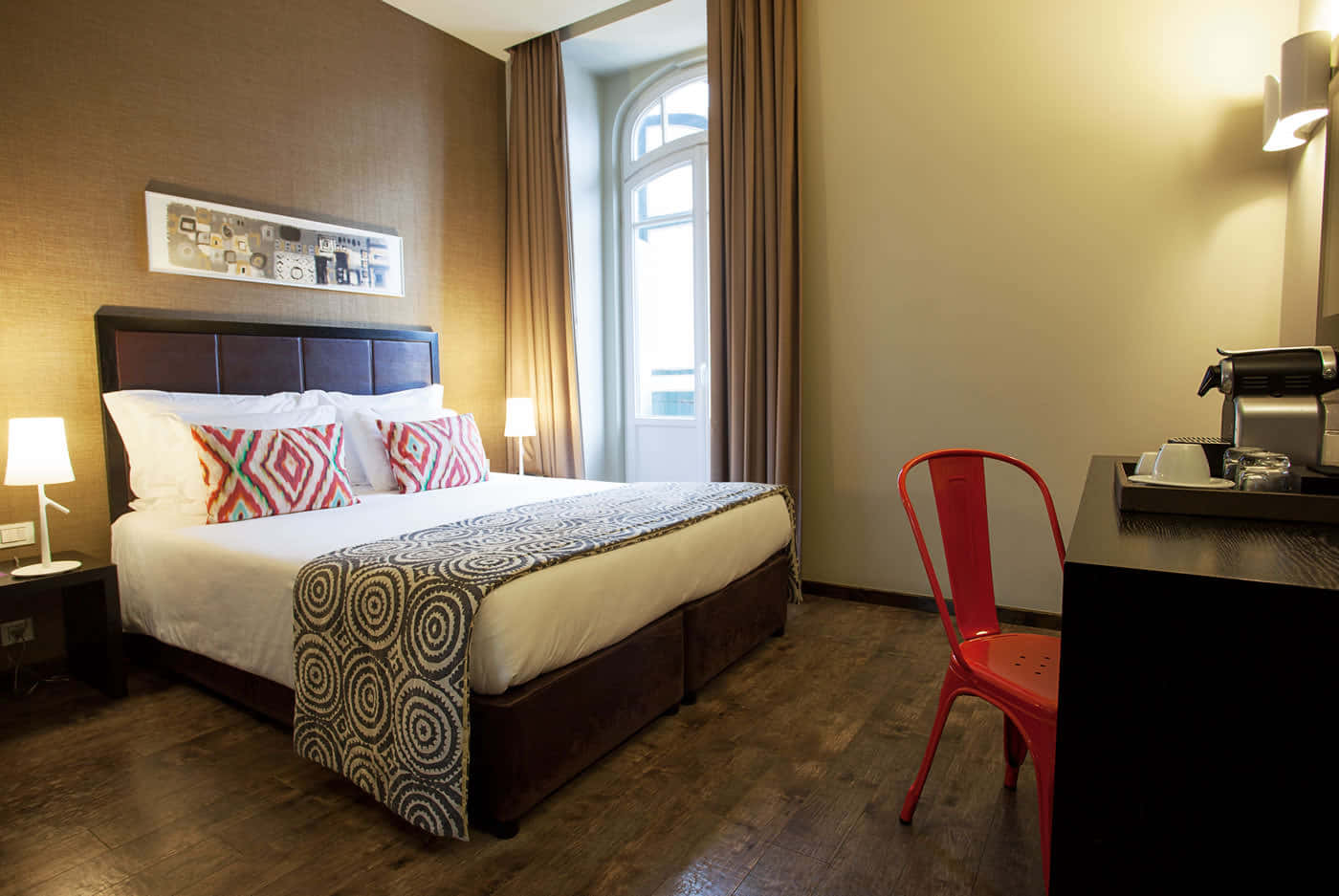 Hotel Room 桌布 壁紙 — 舒適的飯店客房，整齊的床鋪、紅色椅子、木地板，以及床頭燈的溫暖燈光。
