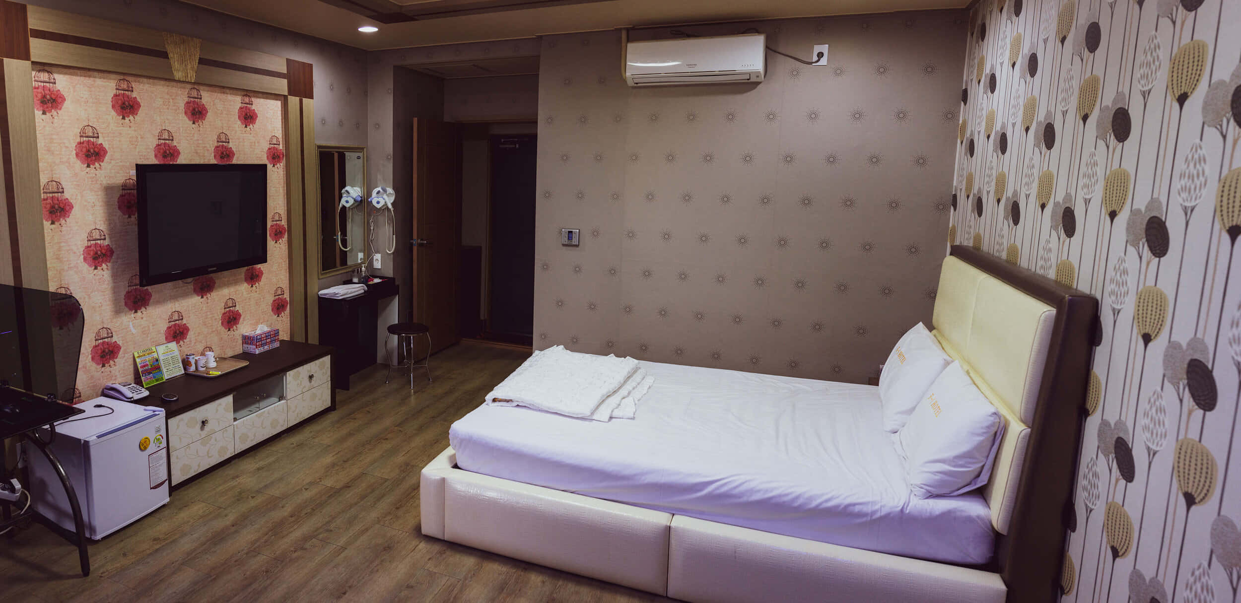 Bedroom 桌布 壁紙 — 舒適的飯店客房，配有整齊鋪好的床、圖案壁紙和木地板，在溫暖的燈光下。