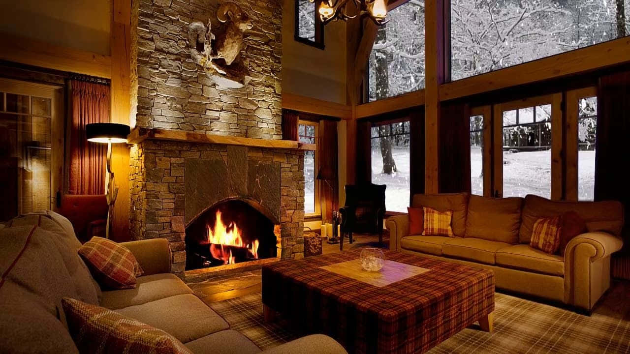 Cozy Winter Cabin 桌布 壁紙 — 舒適質樸的客廳，石砌壁爐溫暖地噼啪作響，旁邊是格子圖案家具，俯瞰白雪皚皚的樹林。