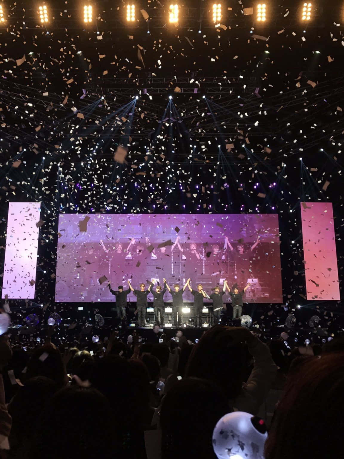 Bts Stage 桌布 壁紙 — 舞台上的表演者在紫色燈光下，於飄落的五彩紙屑中慶祝，下方是歡呼的人群。