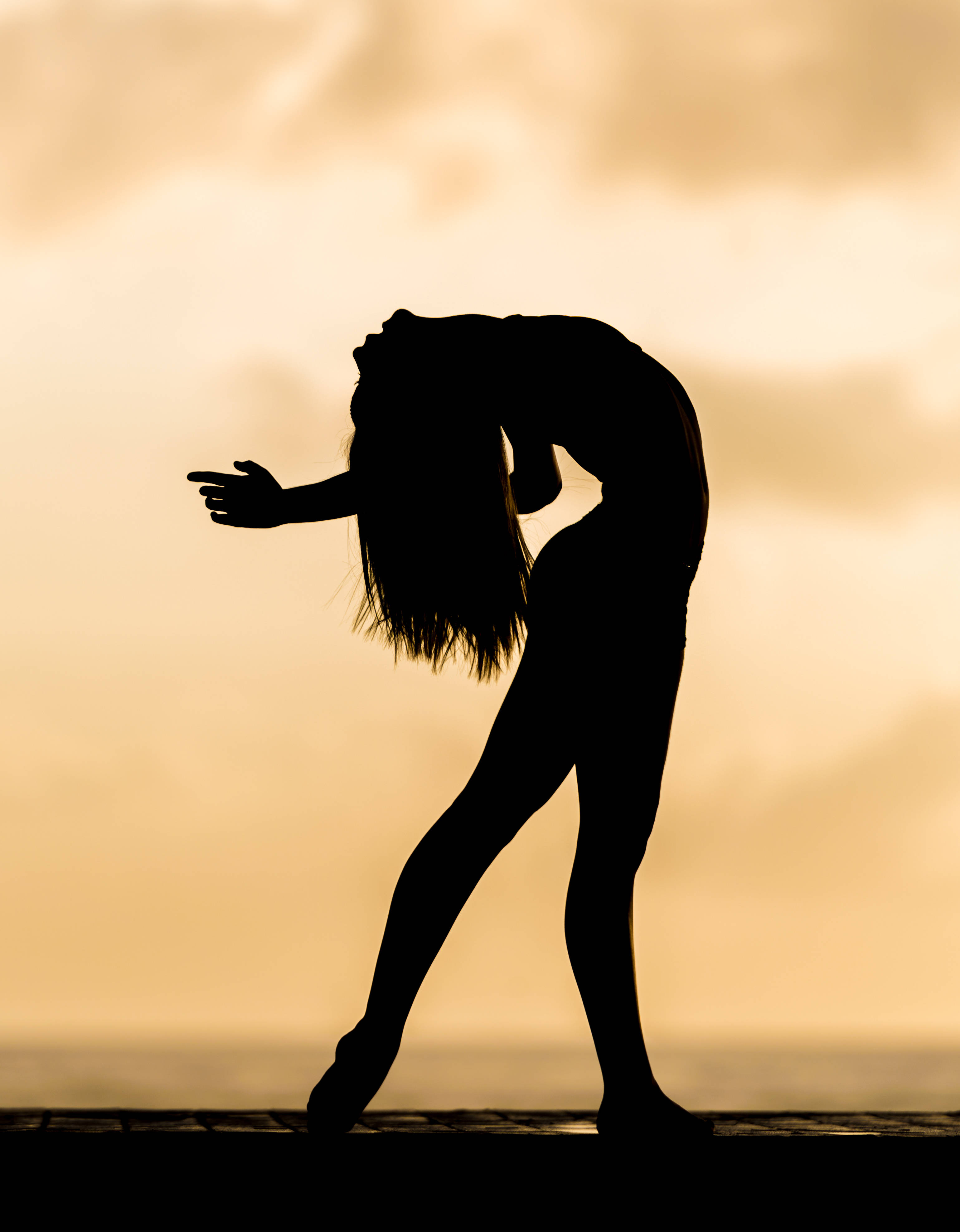 bailando 桌布 壁紙 — 舞者在溫暖的金色日落天空下優雅地向後彎腰的剪影。