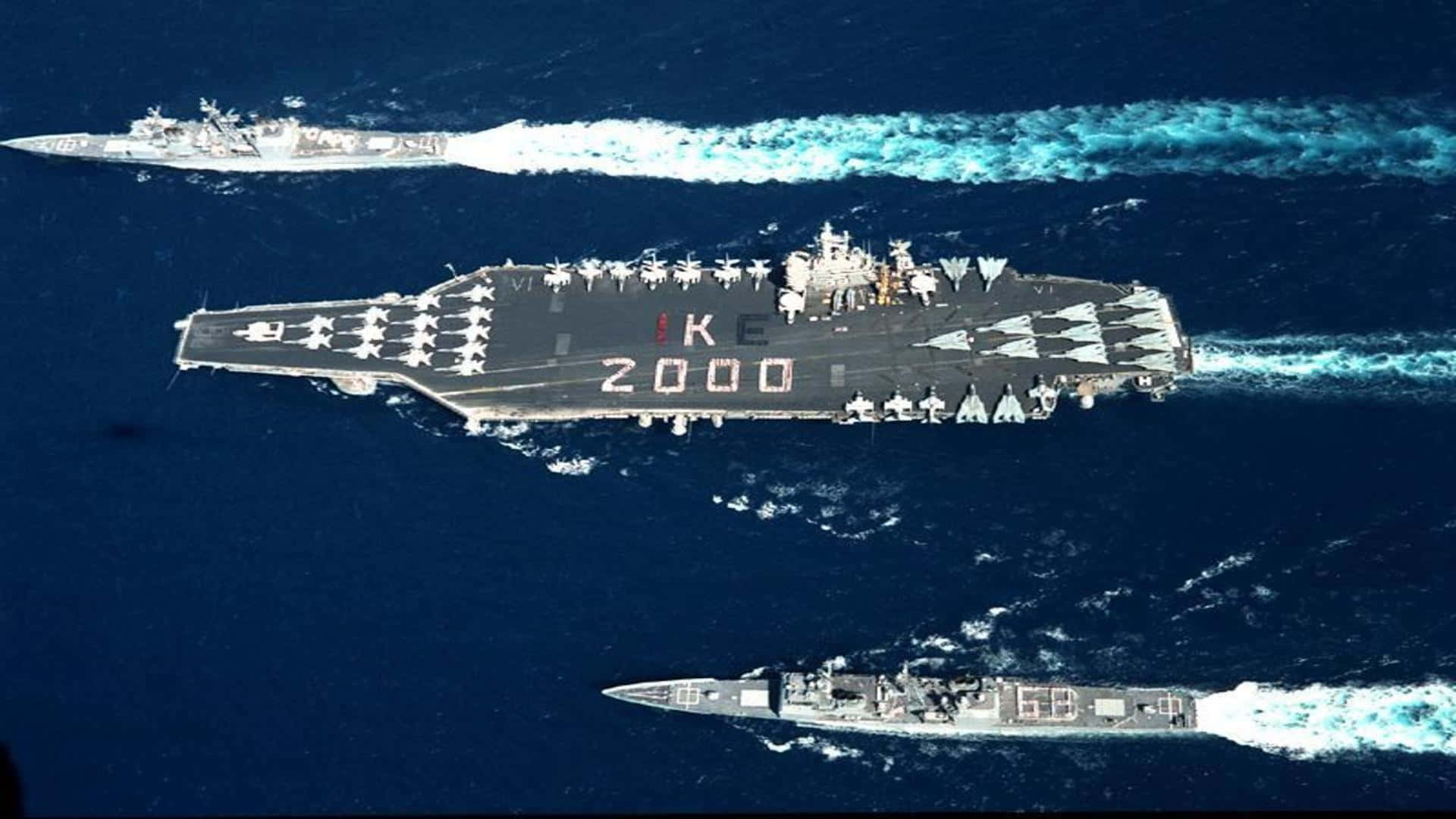 Navy 桌布 壁紙 — 航空母艦IKE 2000在兩艘驅逐艦護航下，劃破深藍色海洋的鳥瞰圖。