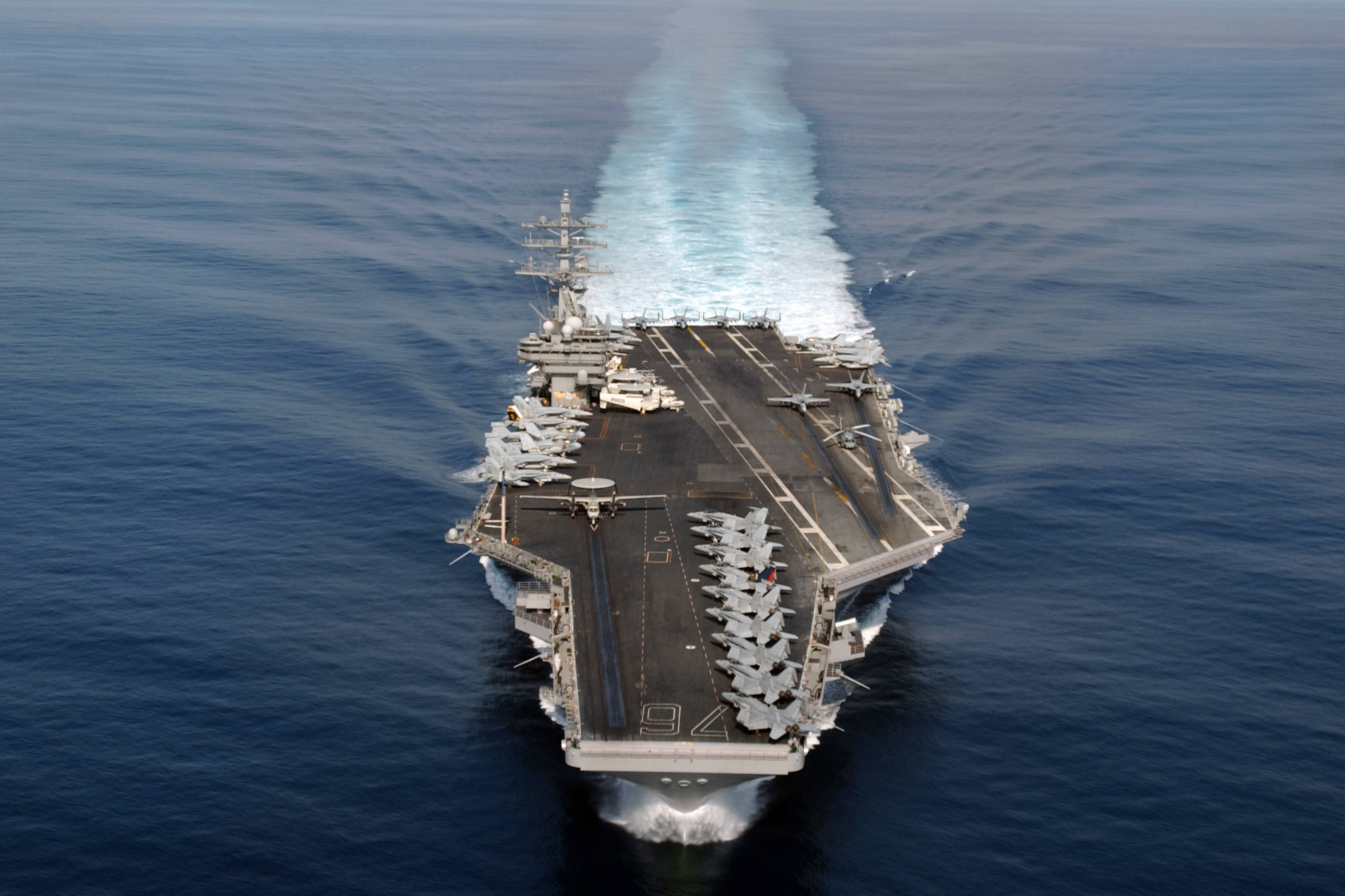 Warship 桌布 壁紙 — 航空母艦劃過深藍色海洋，在其巨大的飛行甲板後留下泡沫般的白色尾跡。