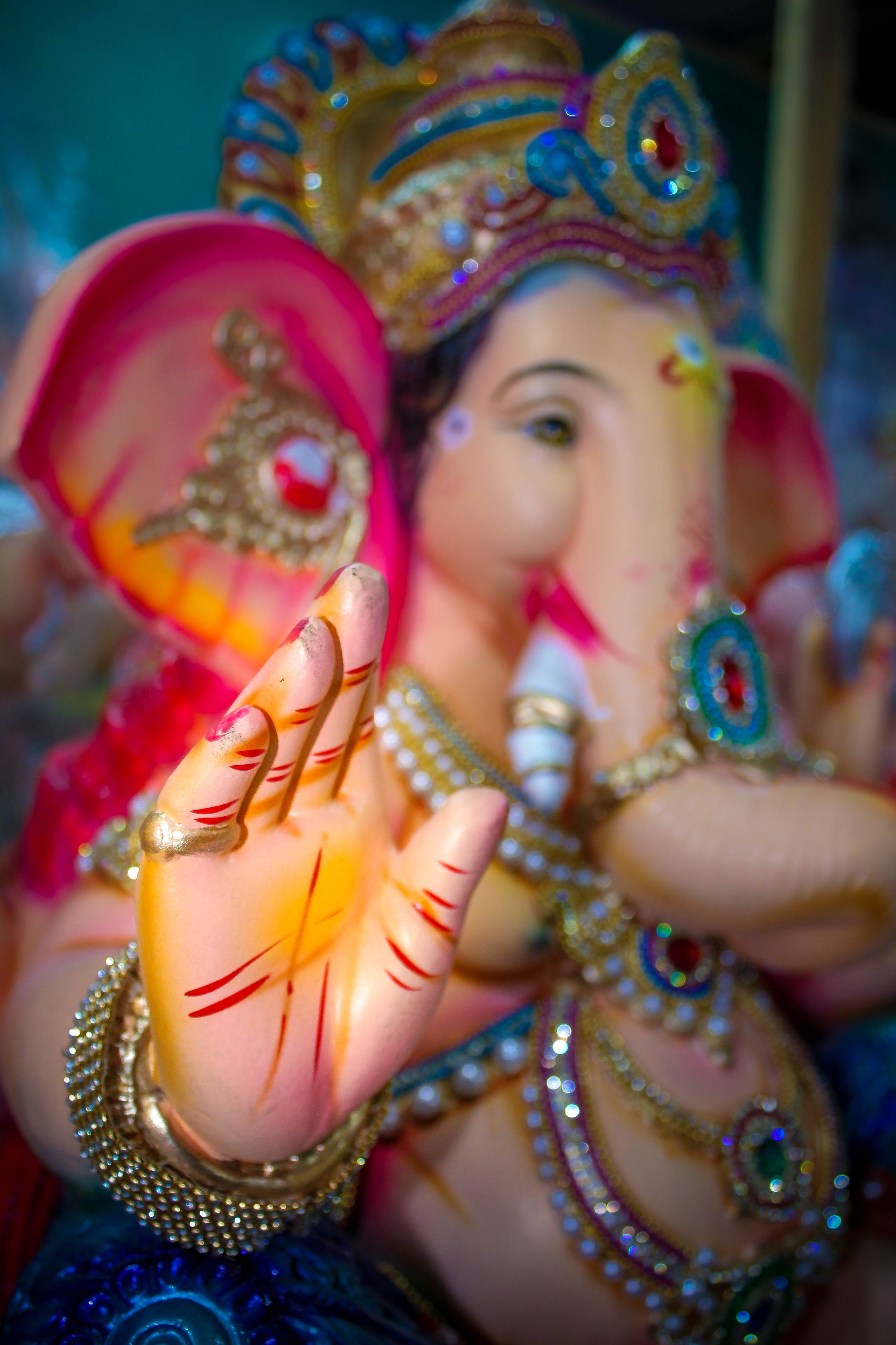 Ganesh Chaturthi 桌布 壁紙 — 色彩繽紛、裝飾華麗的象頭神像特寫，舉起的手上飾有紅色標記和金飾。