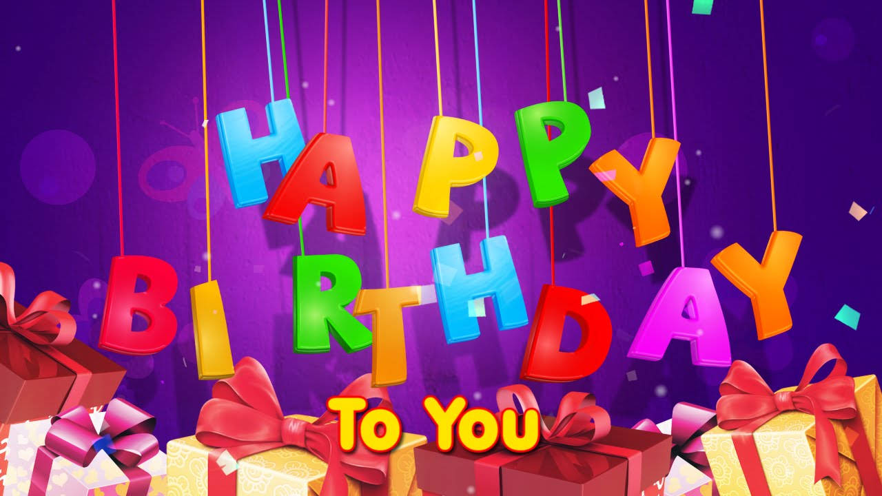 生日快樂 桌布 壁紙 — 色彩繽紛的3D字母拼出「HAPPY BIRTHDAY TO YOU」，懸浮在帶有紅色蝴蝶結的彩色禮物盒上方，背景為紫色散景。
