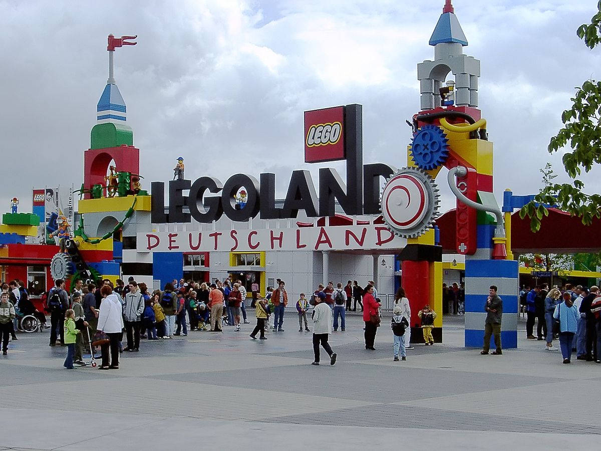 樂高 桌布 壁紙 — 色彩繽紛的LEGO主題入口，通往LEGOLAND Deutschland，擁有彩色積木結構和人群，天空多雲。