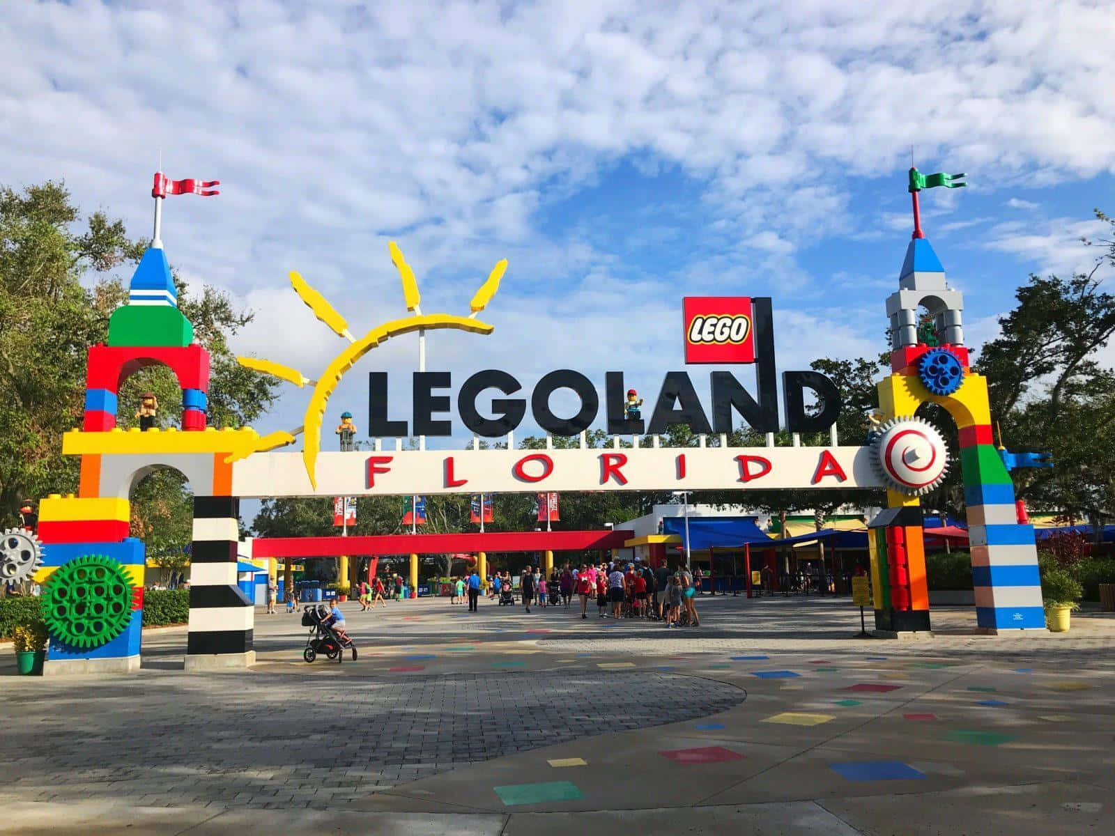 Legoland 桌布 壁紙 — 色彩繽紛的LEGO主題入口拱門，設有彩色積木塔和微笑的太陽，天空部分多雲。