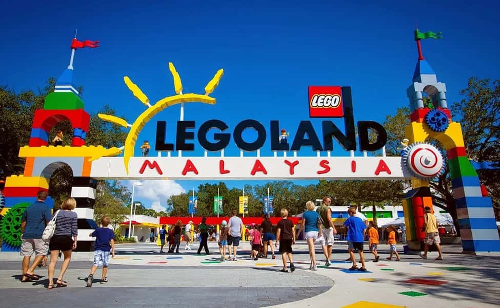 Legoland 桌布 壁紙 — 色彩繽紛的LEGO主題入口拱門，帶有微笑的太陽和彩色積木，在明亮的藍天下歡迎遊客來到馬來西亞LEGOLAND。