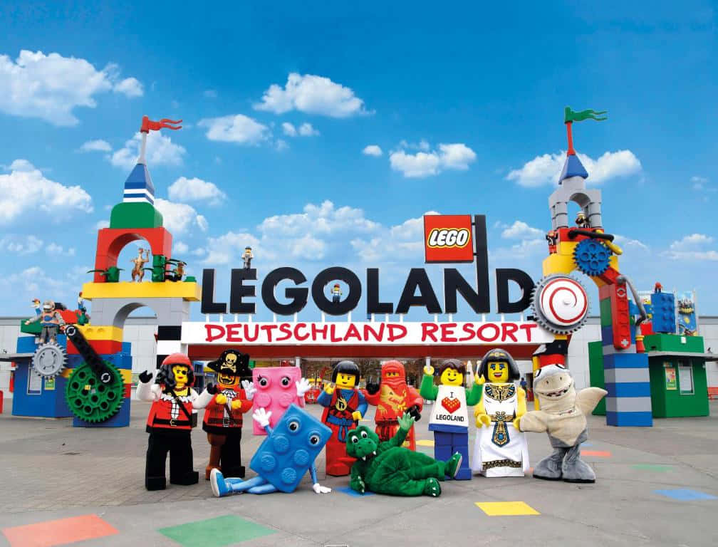 Legoland 桌布 壁紙 — 色彩繽紛的LEGO角色在晴朗的藍天下，於色彩繽紛的LEGOLAND Deutschland Resort入口前愉快地擺姿勢。