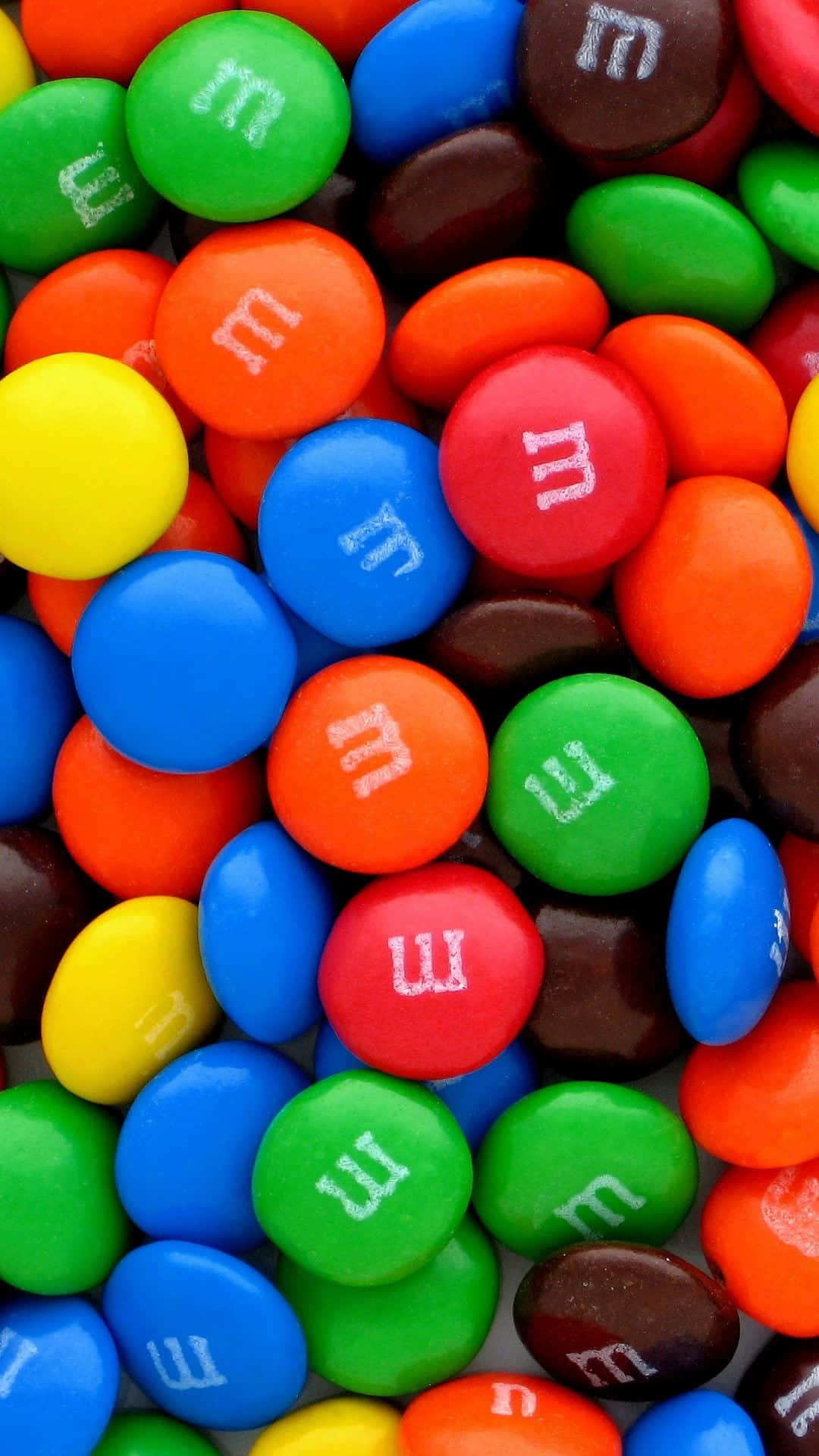 M 桌布 壁紙 — 色彩繽紛的M&M's糖果特寫，白色「m」標誌密集散落。