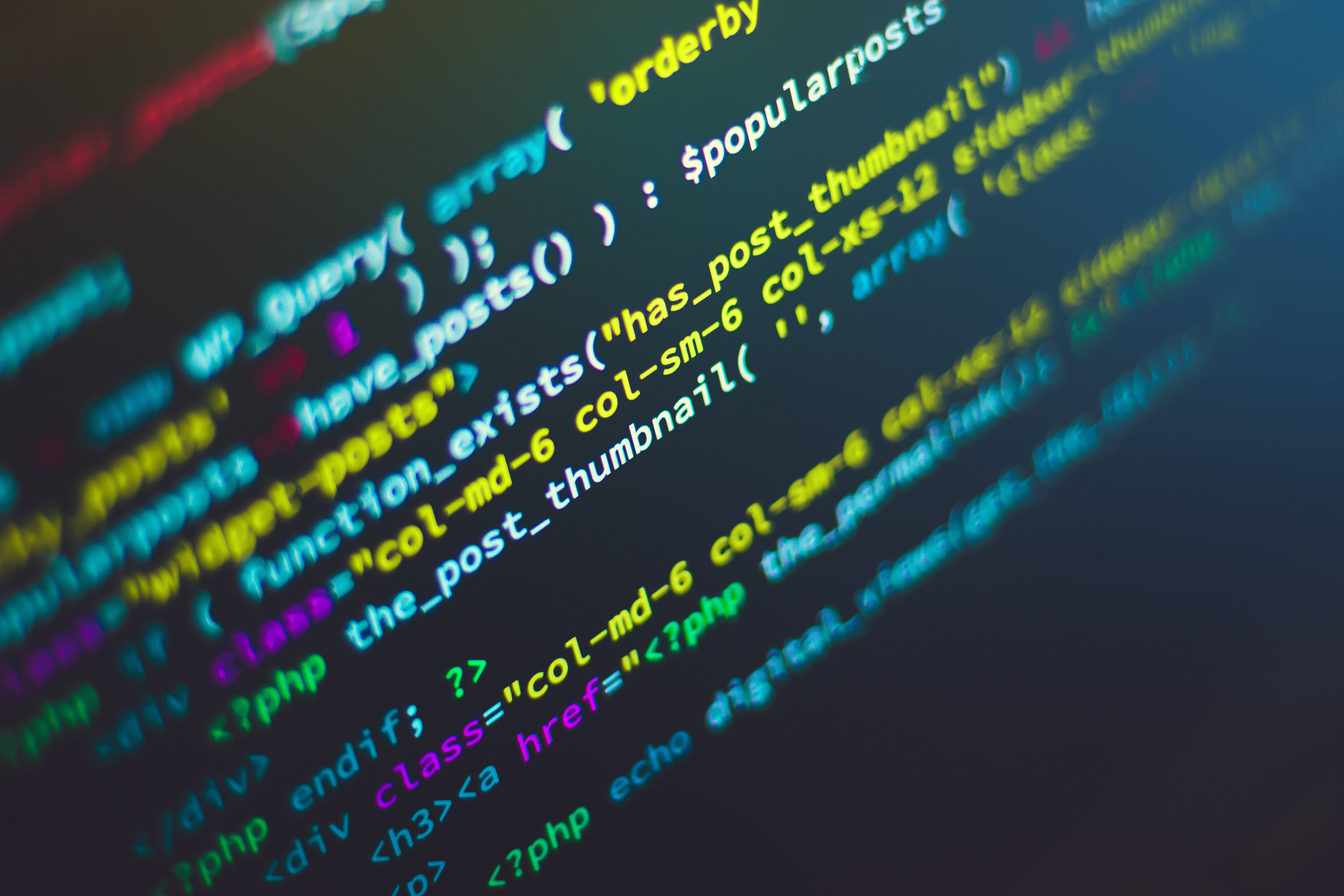 程式設計 桌布 壁紙 — 色彩繽紛的PHP代碼發出鮮豔光芒，以對角線漂浮在淺景深的暗色螢幕上。
