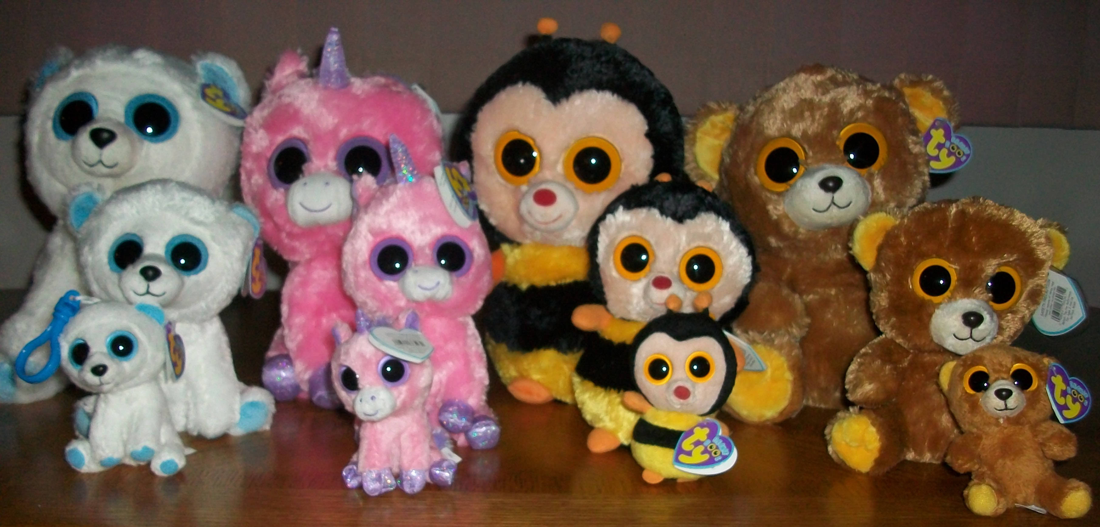 Beanie 桌布 壁紙 — 色彩繽紛的Ty Beanie Boo毛絨玩具系列，包括熊、獨角獸和企鵝，排列在木質表面上。