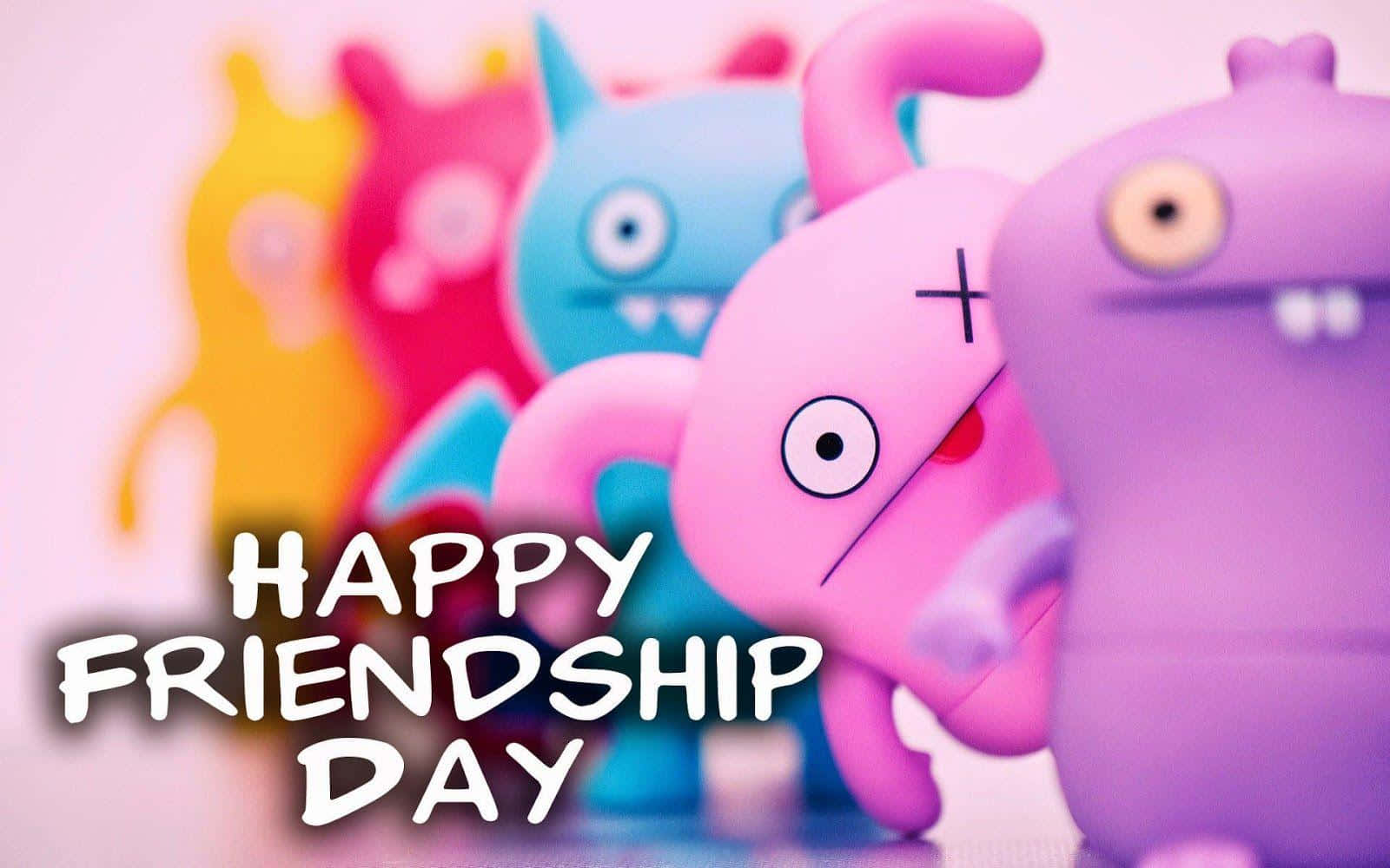 Friendship Day 桌布 壁紙 — 色彩繽紛的Uglydoll玩具，背景柔和模糊，帶有「HAPPY FRIENDSHIP DAY」文字。