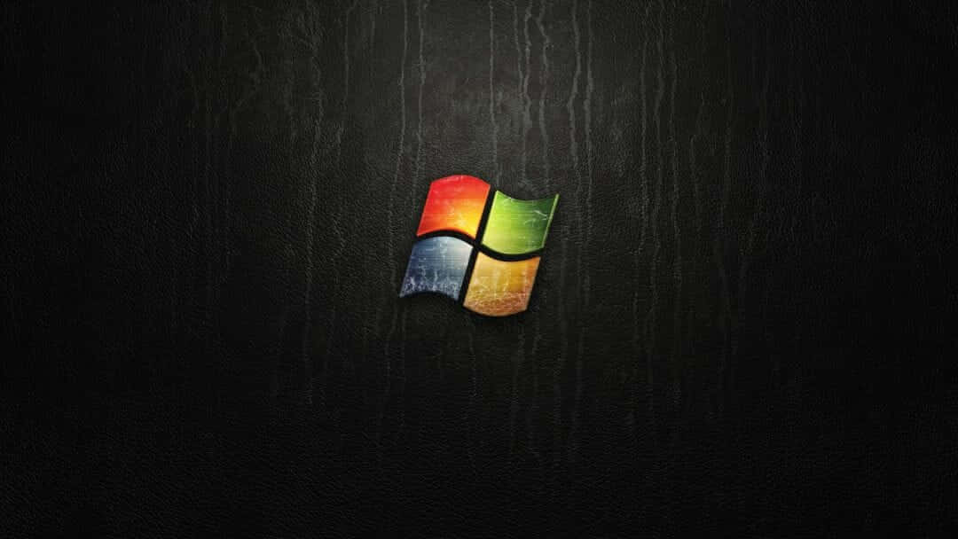Windows Xp Logo 桌布 壁紙 — 色彩繽紛的Windows標誌在帶有細微垂直條紋的深色紋理背景上發光。