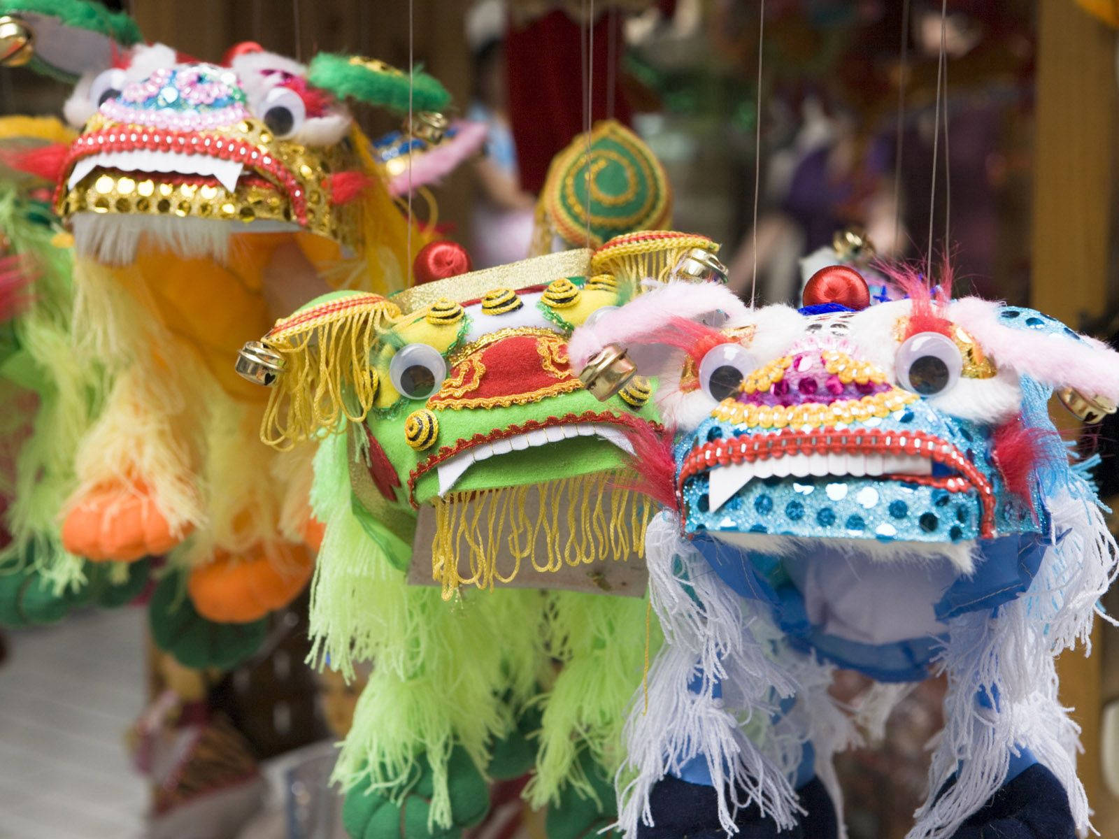 龍 桌布 壁紙 — 色彩繽紛的傳統中國舞獅面具懸掛在熙熙攘攘的市場攤位中。