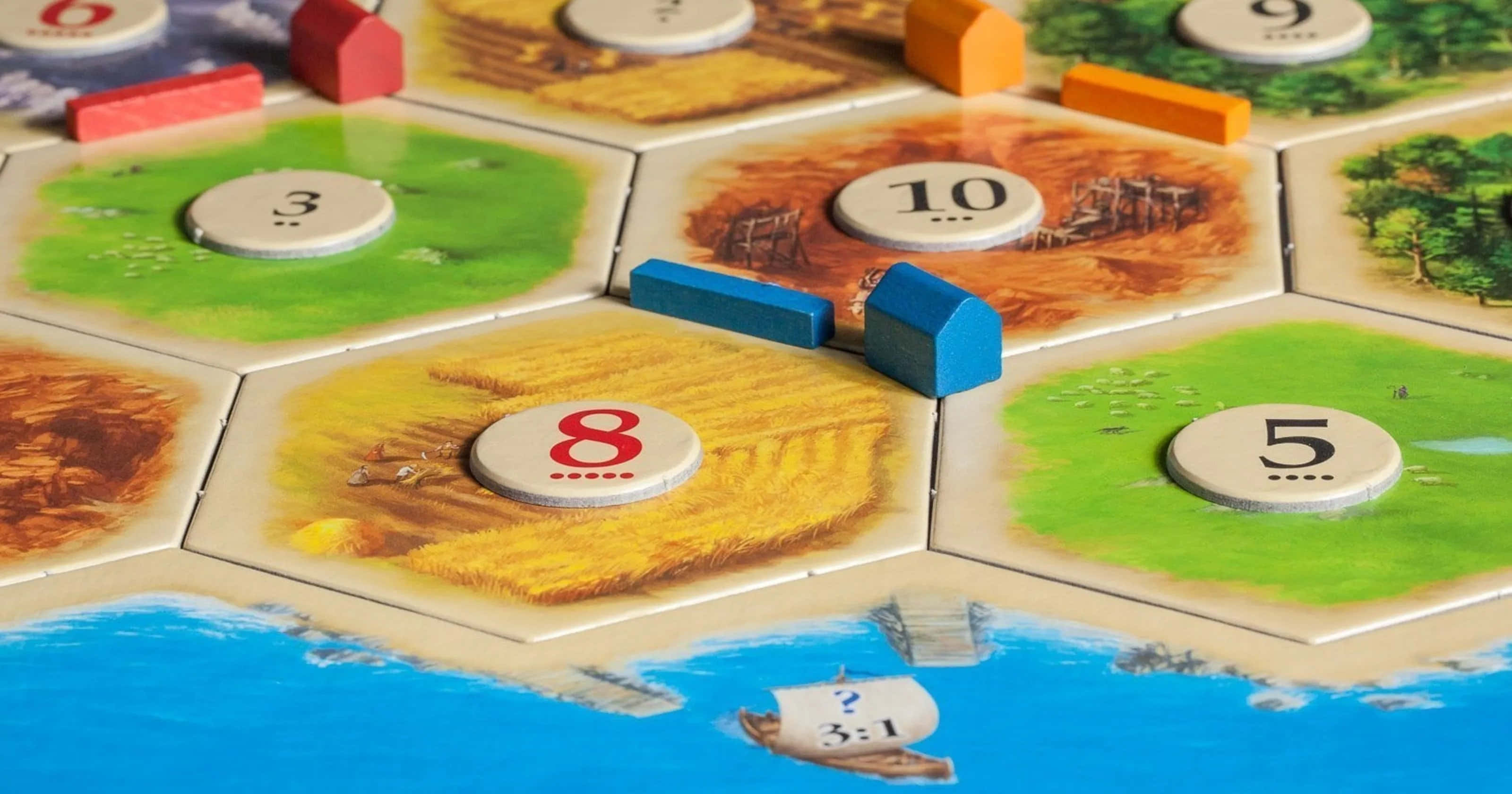 game 桌布 壁紙 — 色彩繽紛的六角形棋盤遊戲特寫，帶有編號的棋子及藍色小屋，置於有紋理的表面上。