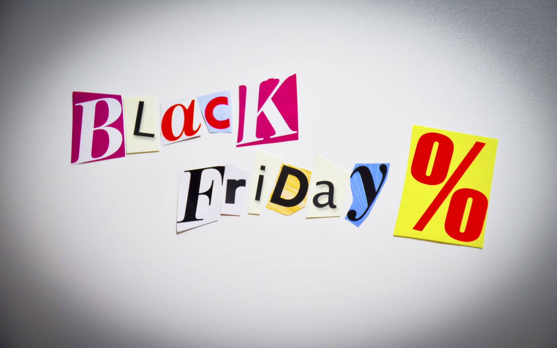 Friday 桌布 壁紙 — 色彩繽紛的剪出字母拼出「Black Friday」和一個黃色百分號，排列在純灰色背景上。