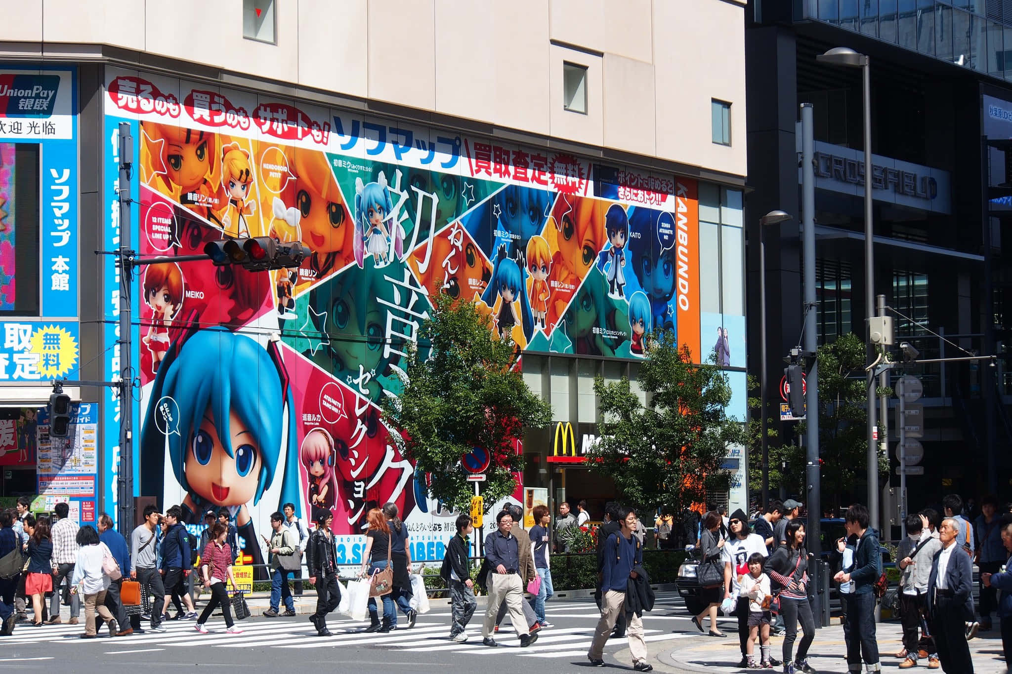 Otaku Culture 桌布 壁紙 — 色彩繽紛的動漫角色壁畫覆蓋東京一棟建築物，行人在明亮日光下穿過繁忙街道。