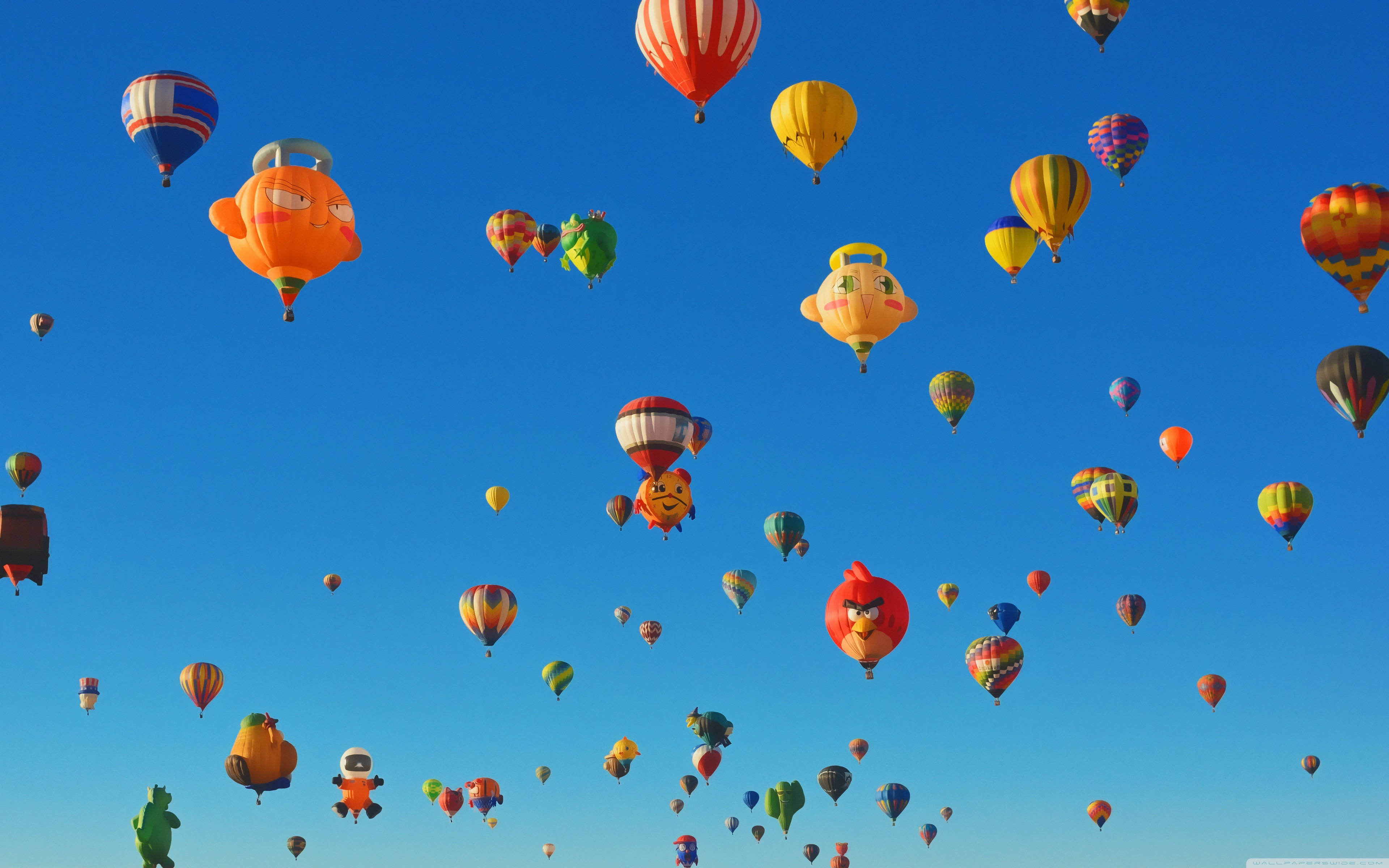 Balloon 桌布 壁紙 — 色彩繽紛的卡通角色形狀熱氣球在清澈的藍天上歡快地飄浮。