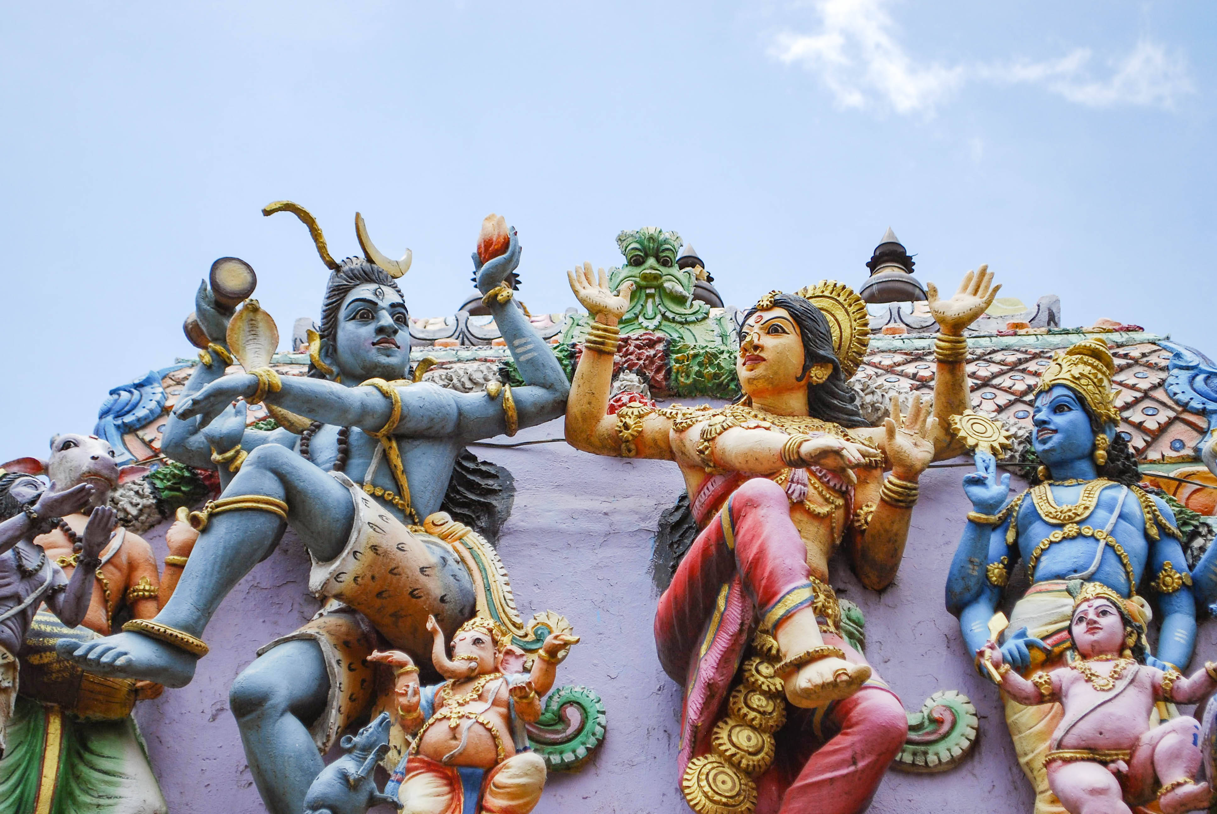 Indian 桌布 壁紙 — 色彩繽紛的印度教神像以動態姿勢裝飾著寺廟屋頂，背景是清澈的藍天。