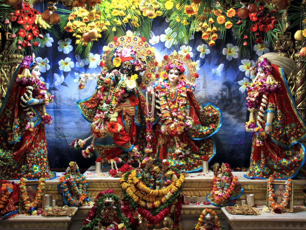 Hindu Temple 桌布 壁紙 — 色彩繽紛的印度教神祇，裝飾著色彩鮮豔的花環和精緻的珠寶，站在裝飾華麗的祭壇上，上方是花朵組成的華蓋。