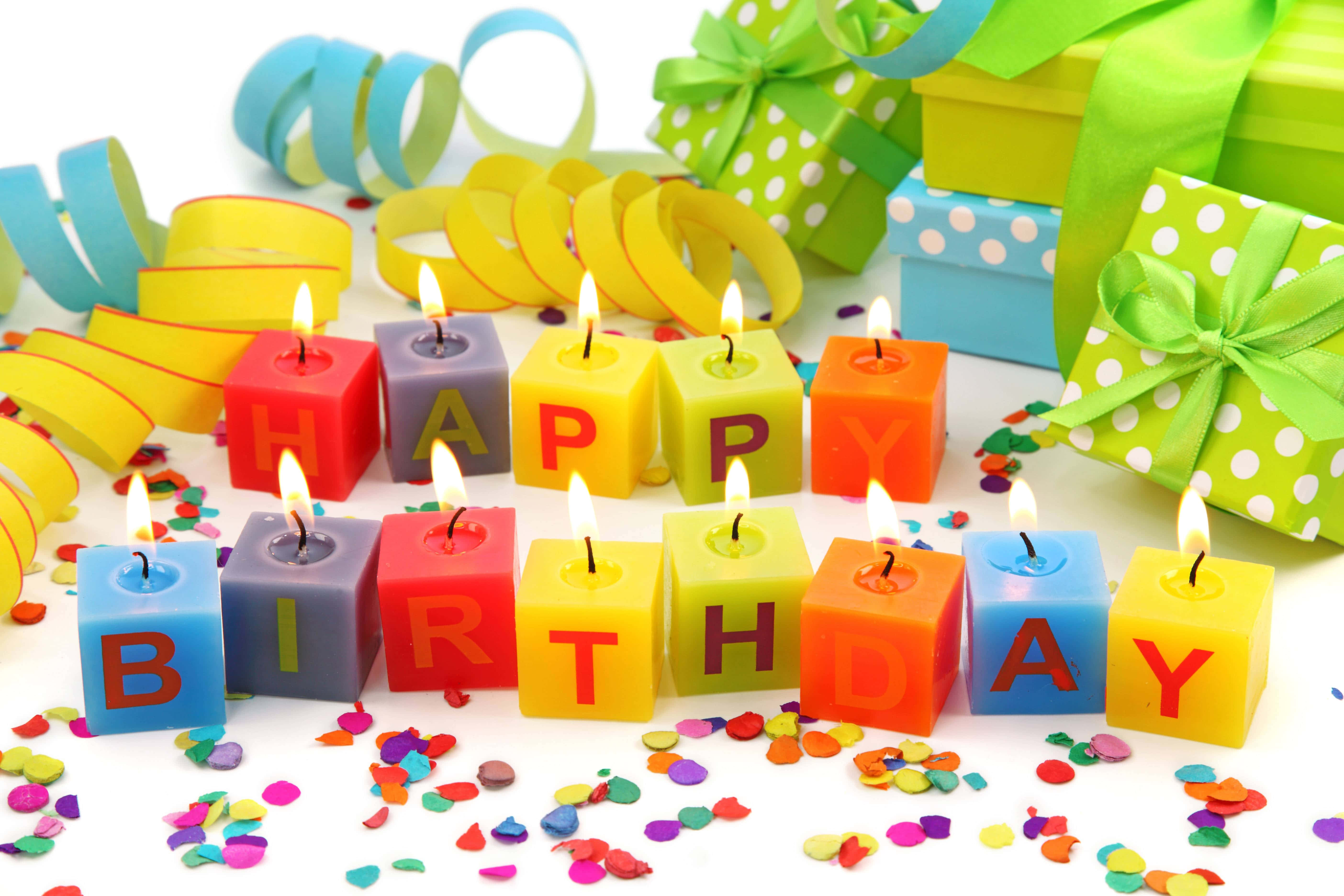 生日快樂 桌布 壁紙 — 色彩繽紛的塊狀蠟燭拼出 happy birthday，在五彩紙屑和包裝禮物中溫暖地發光。