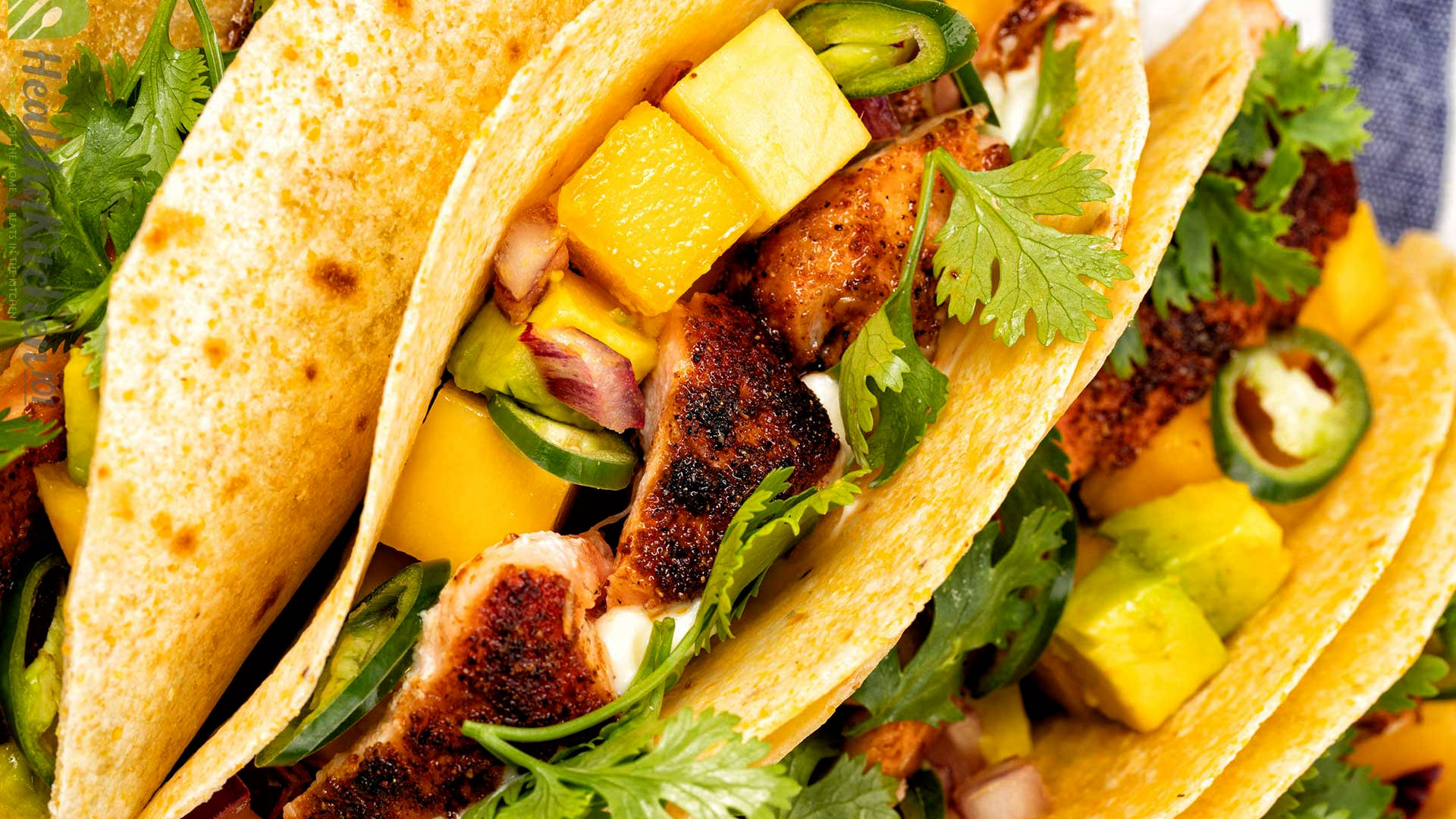 Tacos 桌布 壁紙 — 色彩繽紛的墨西哥夾餅特寫，內餡有烤雞肉、芒果、酪梨和香菜，放在軟玉米餅上。