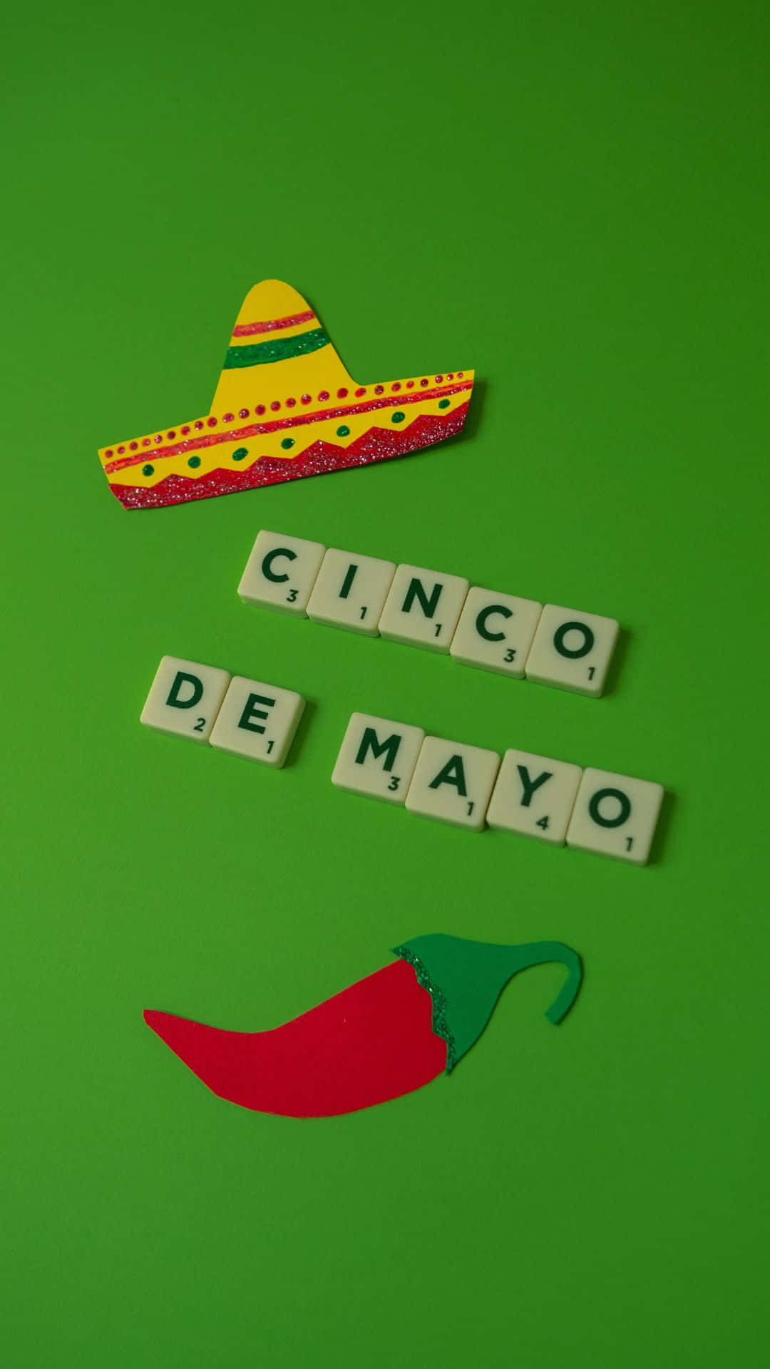 Cinco De Mayo 桌布 壁紙 — 色彩繽紛的墨西哥闊邊帽和紅辣椒，在亮綠色背景上，兩旁放著拼出「CINCO DE MAYO」的 Scrabble 字母牌。