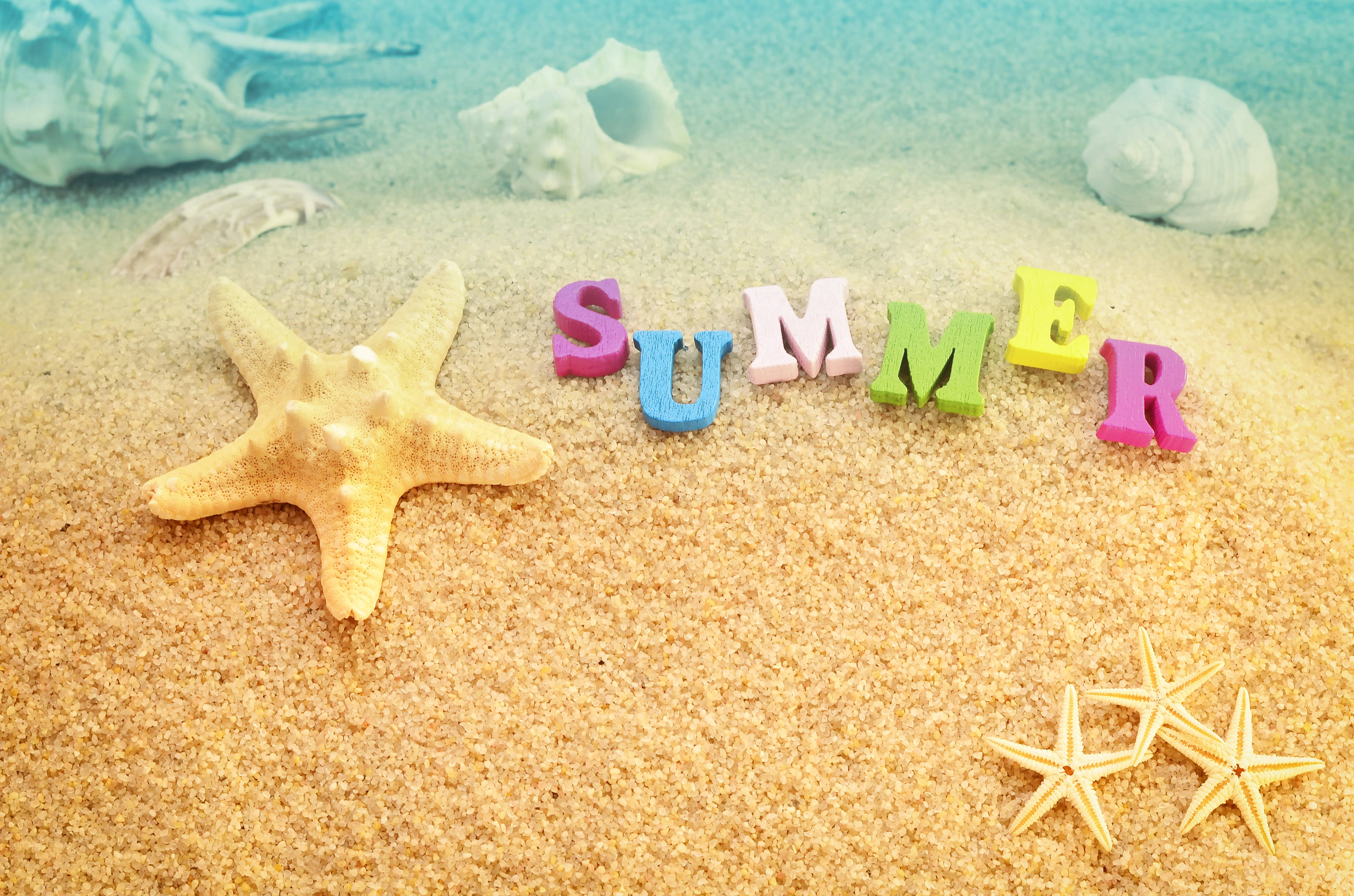 4K Summer 桌布 壁紙 — 色彩繽紛的字母拼出夏天，在溫暖陽光下躺在金色沙灘上，旁邊有海星和貝殼。