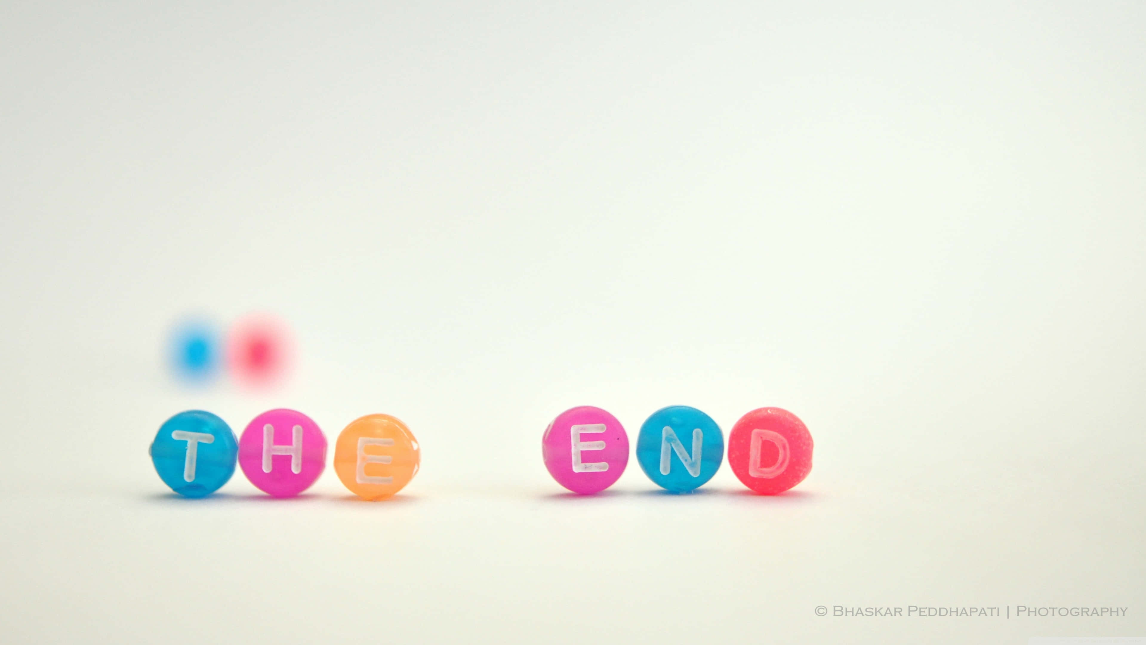 the end 桌布 壁紙 — 色彩繽紛的字母珠子拼出「THE END」，放在純白色表面上，背景柔和散景。