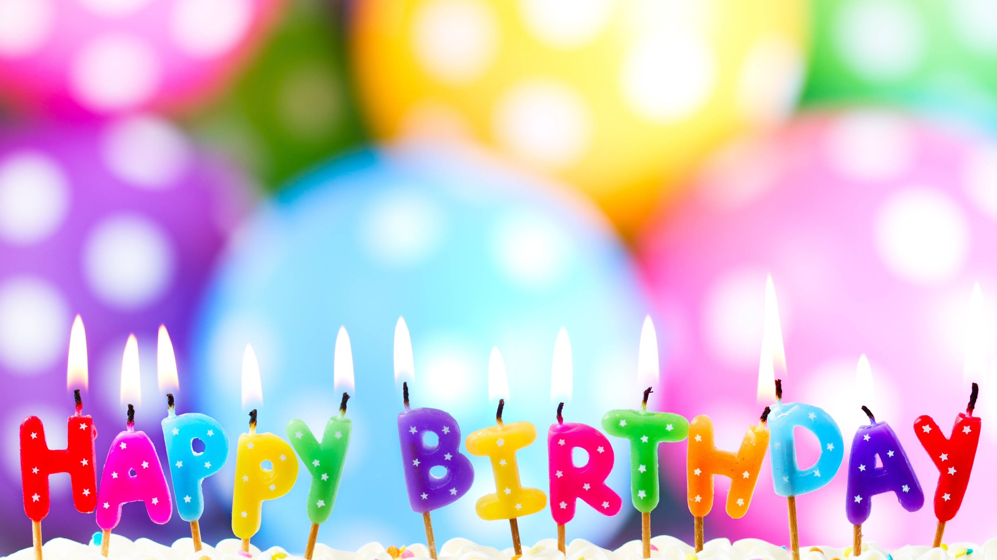 蛋糕 桌布 壁紙 — 色彩繽紛的字母蠟燭在糖霜蛋糕上拼出 happy birthday，背景有模糊的波點氣球。