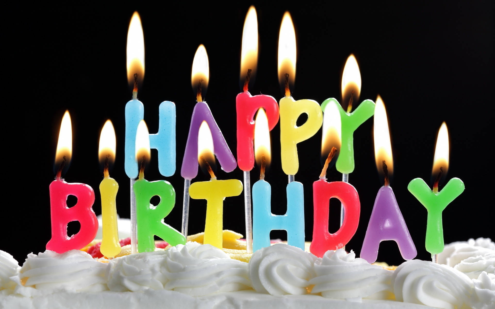 蛋糕 桌布 壁紙 — 色彩繽紛的字母蠟燭拼出 happy birthday，在黑色背景的糖霜蛋糕上溫暖地發光。