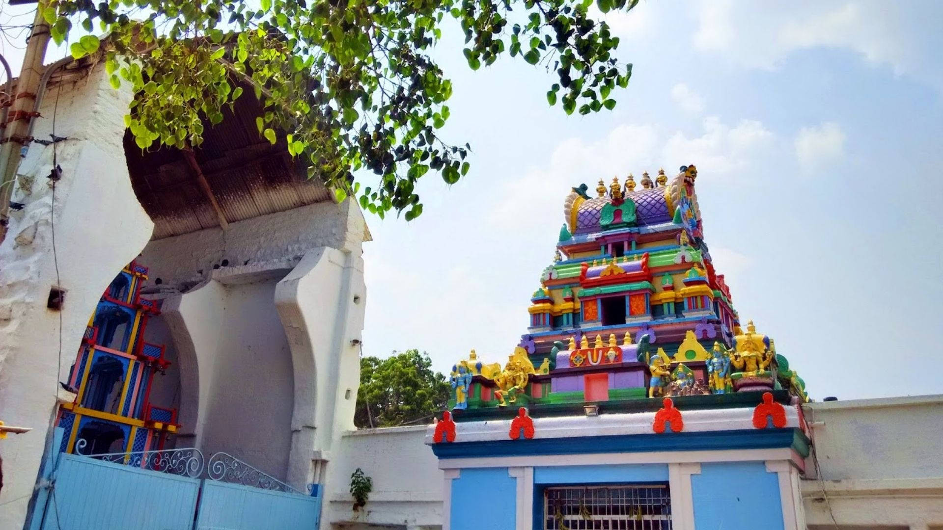 Hyderabad 桌布 壁紙 — 色彩繽紛的寺廟塔樓在晴朗的藍天下聳立，周圍環繞著茂密的綠色樹枝。