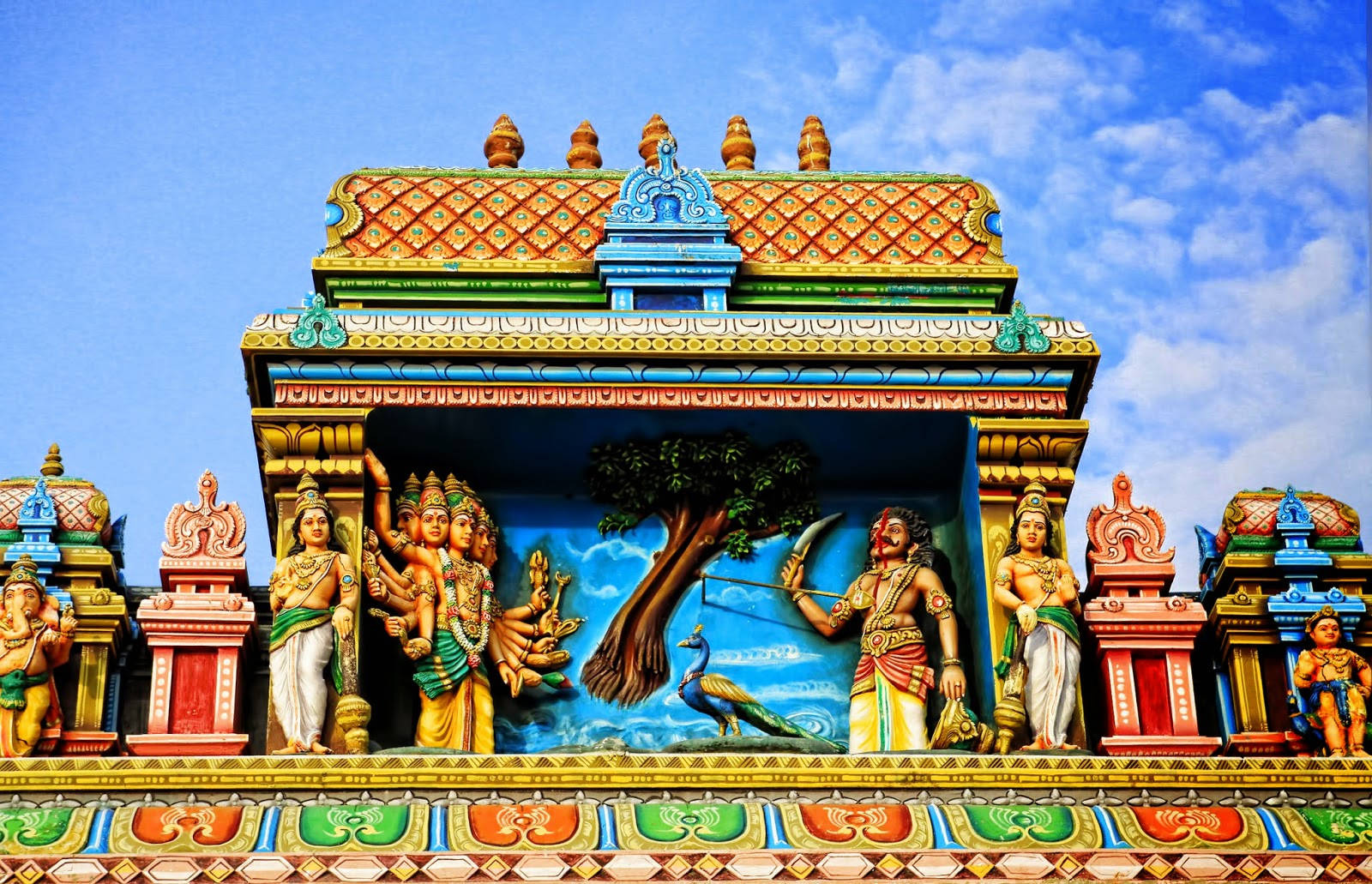 Hindu Temple 桌布 壁紙 — 色彩繽紛的寺廟門塔，裝飾著色彩鮮豔的印度教神祇和神話生物雕像，背景是明亮的藍天。