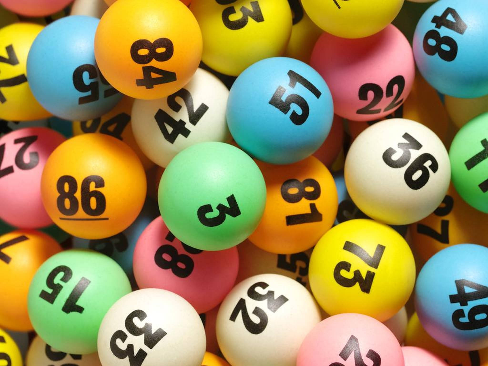 Lottery 桌布 壁紙 — 色彩繽紛的彩券球特寫，上面有粗體黑色數字，雜亂地堆成一堆。