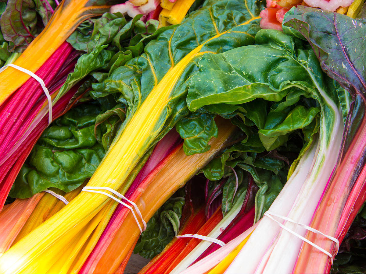Food Photography 桌布 壁紙 — 色彩繽紛的彩虹甜菜束，綠色葉片和彩色莖稈以鮮豔色調捆綁。