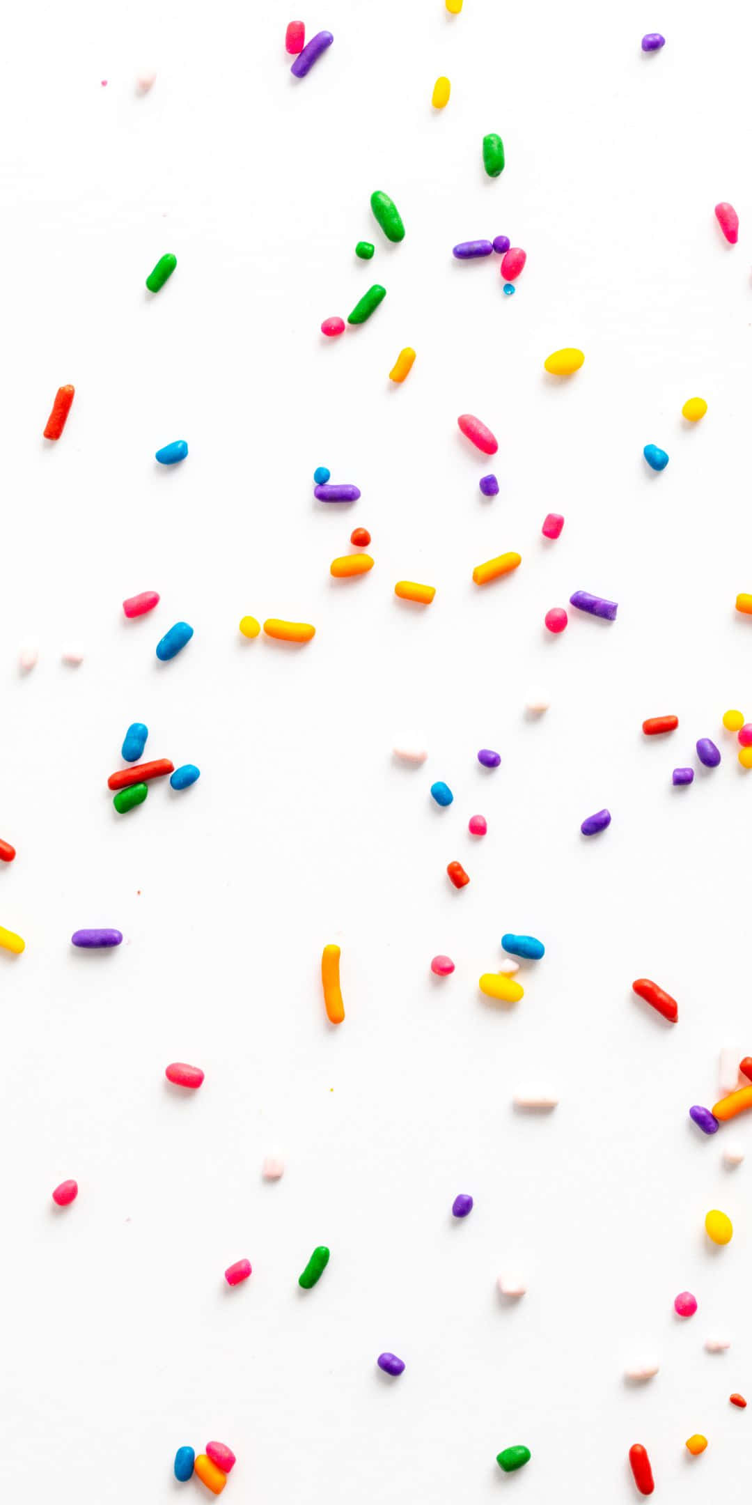 Sprinkles 桌布 壁紙 — 色彩繽紛的彩虹糖針散落在潔白表面上，營造出俏皮甜點的氛圍。
