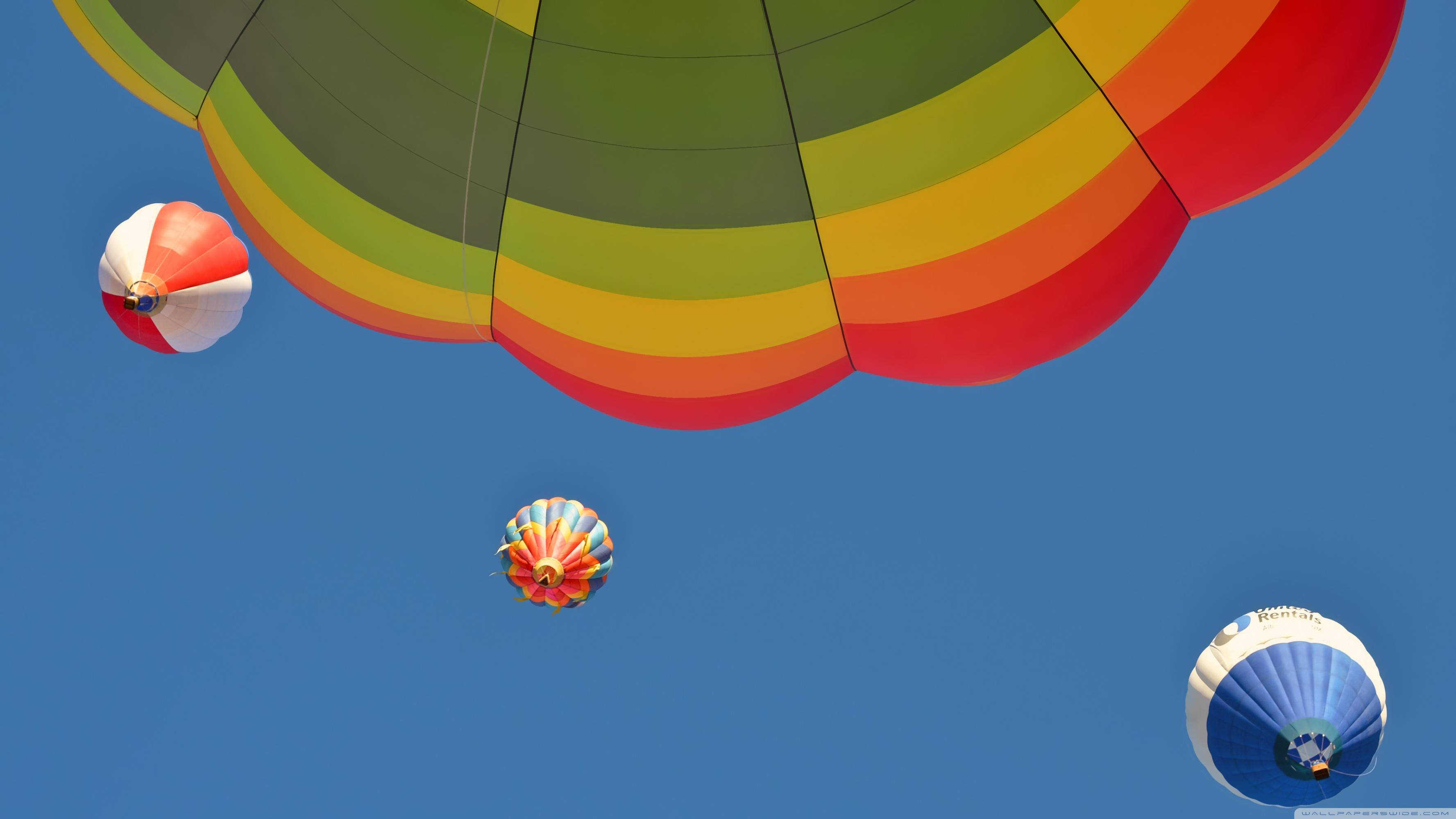 Balloon 桌布 壁紙 — 色彩繽紛的彩虹色熱氣球在清澈的藍天中優雅地飄浮。