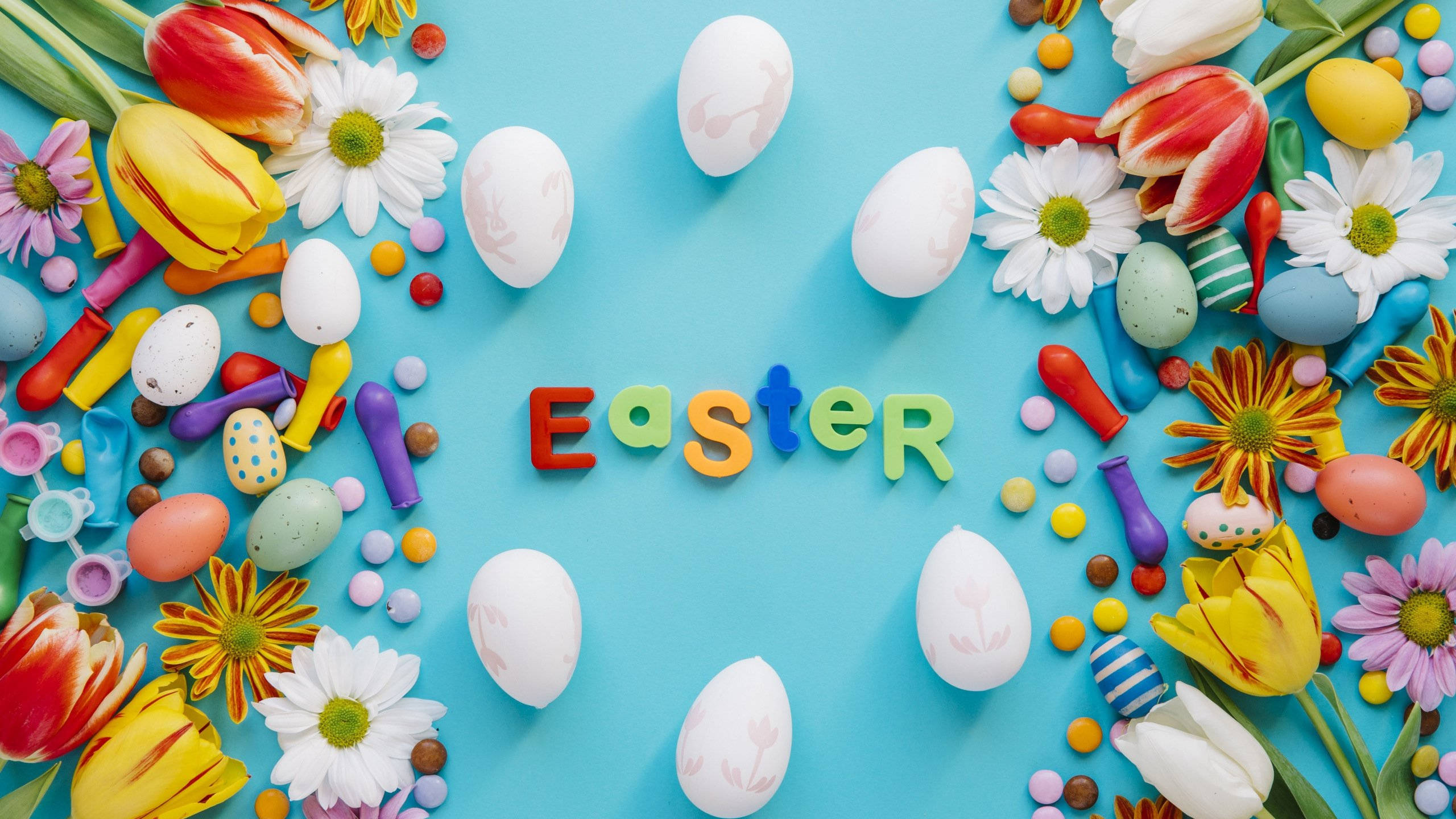 Easter 桌布 壁紙 — 色彩繽紛的復活節蛋、花朵和糖果圍繞著「Easter」這個詞排列在明亮的藍色背景上。