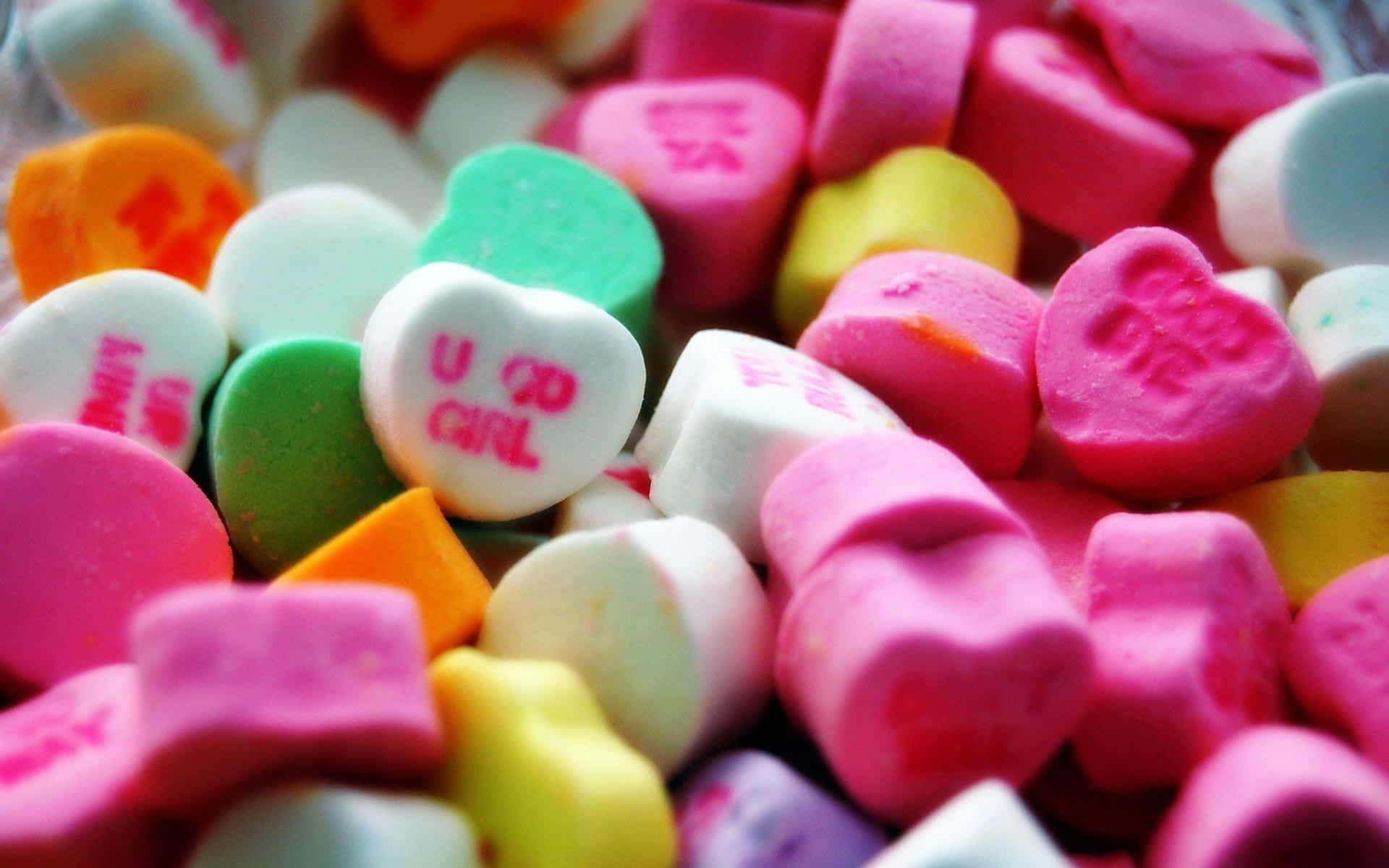 Sweet 桌布 壁紙 — 色彩繽紛的情人節心形糖果特寫，上面印有『U SO GIRL』和『BE MINE』等彩色訊息。