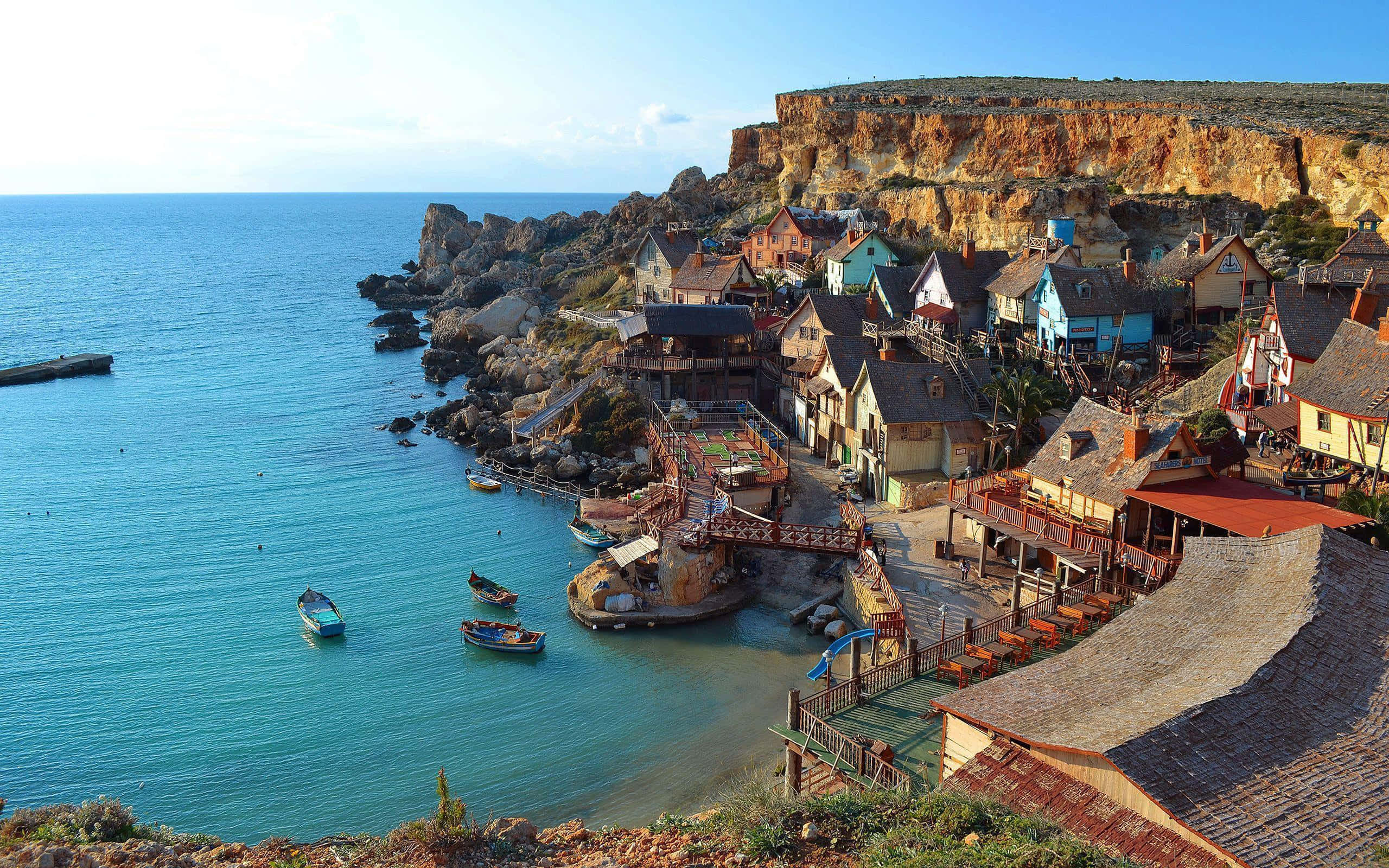 Malta 桌布 壁紙 — 色彩繽紛的懸崖村莊，擁有陶土屋頂，沿著碧綠海水而建，在明亮的藍天下。