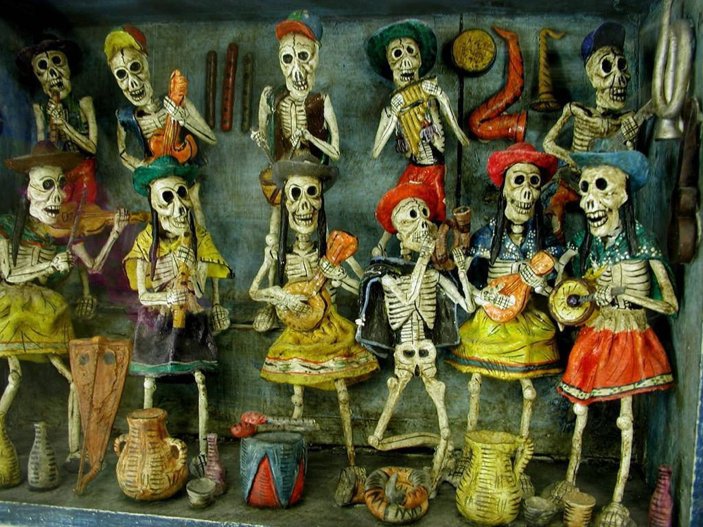 Dia De Los Muertos 桌布 壁紙 — 色彩繽紛的手工糖骷髏穿著傳統墨西哥服飾，在節日展示中演奏樂器。