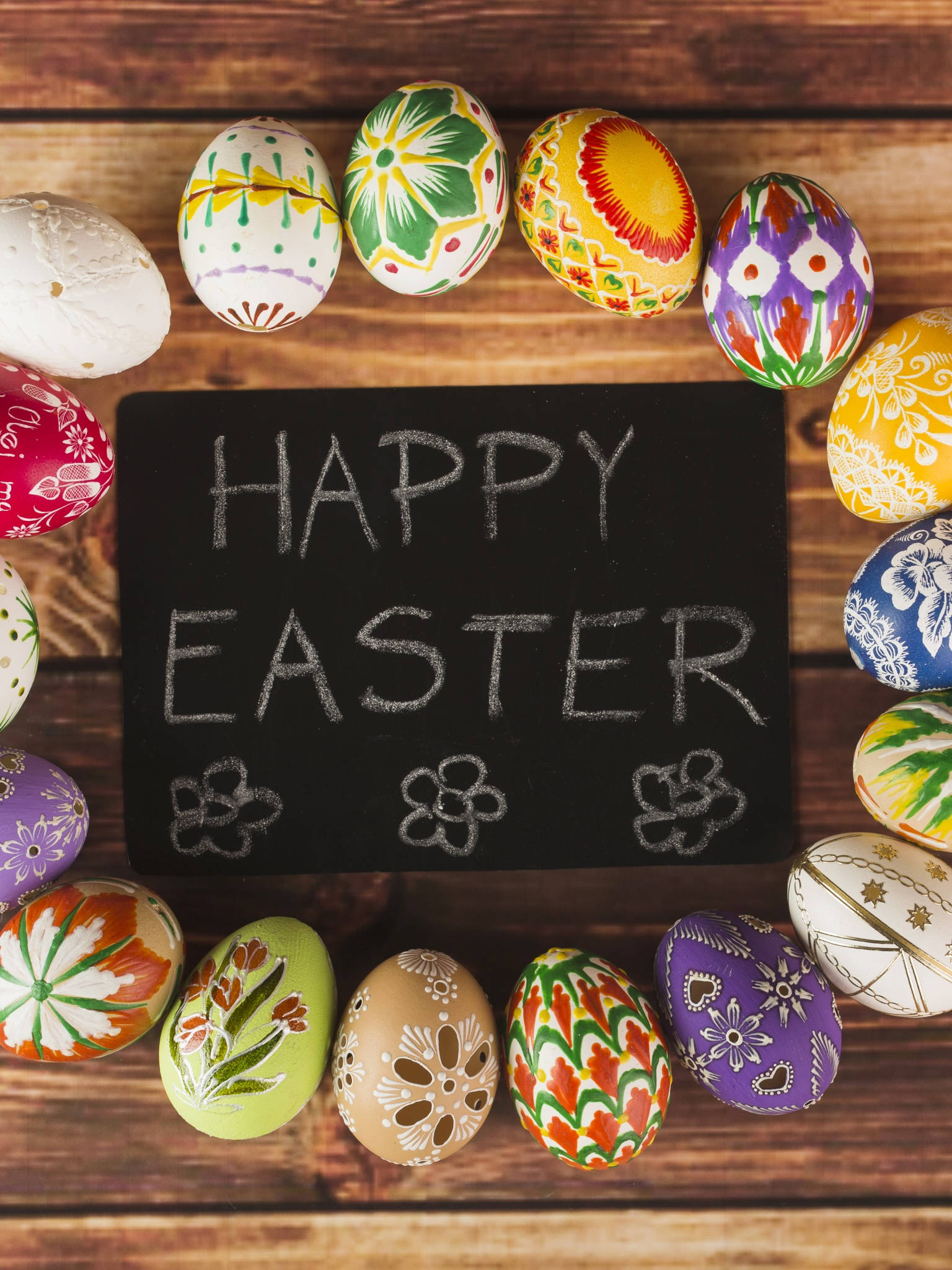 Easter Phone 桌布 壁紙 — 色彩繽紛的手繪復活蛋圍繞著一塊黑板，上面用白色粉筆寫著「HAPPY EASTER」，放在質樸的木質表面上。