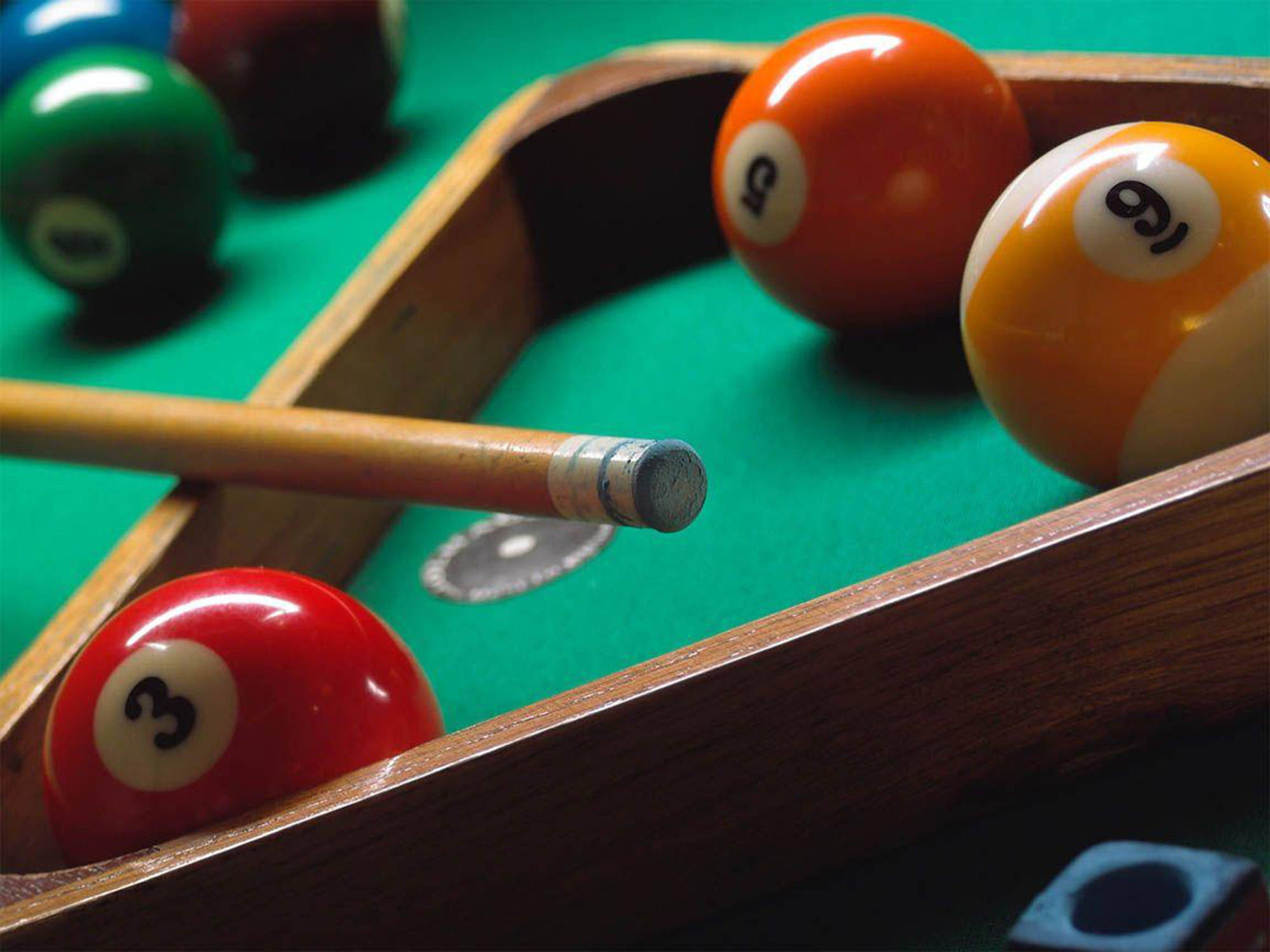 Snooker 桌布 壁紙 — 色彩繽紛的撞球和球桿放在木製邊框附近鮮綠色絨布上的特寫。