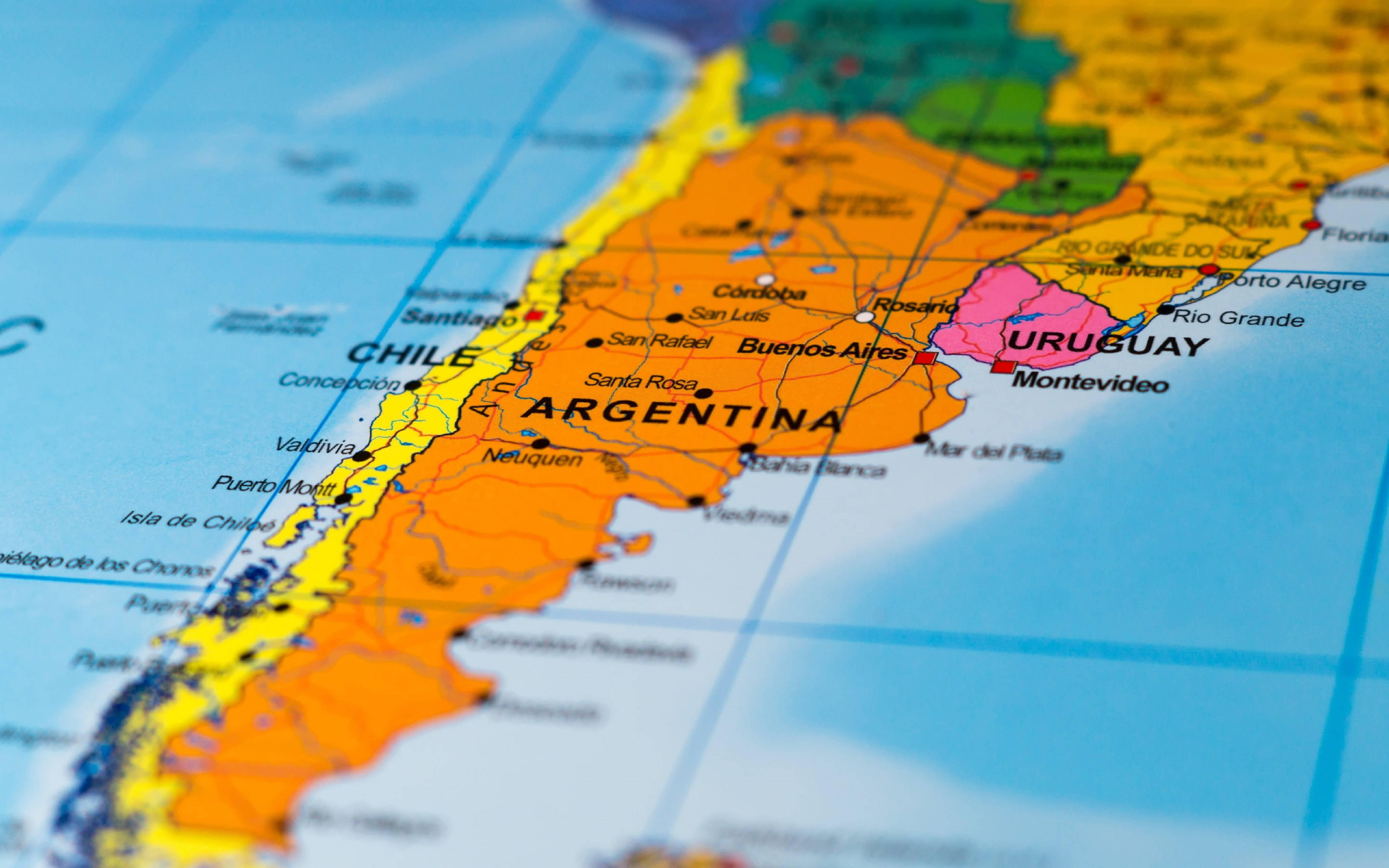 Argentina 桌布 壁紙 — 色彩繽紛的政治地圖特寫，突出阿根廷、智利和烏拉圭，背景為模糊的海洋。