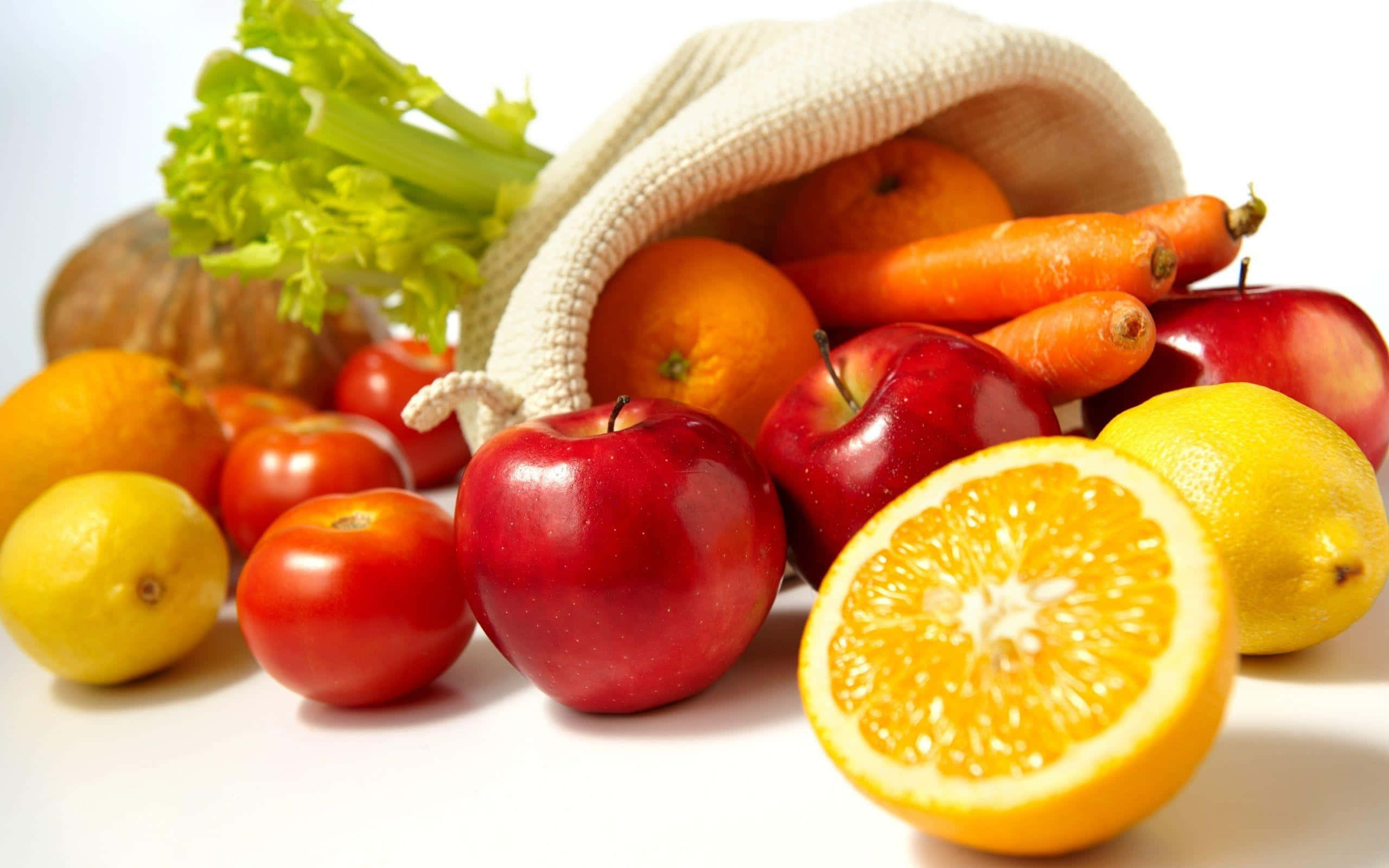 Healthy Food 桌布 壁紙 — 色彩繽紛的新鮮水果和蔬菜從米色布袋中溢出，背景是潔淨的白色。