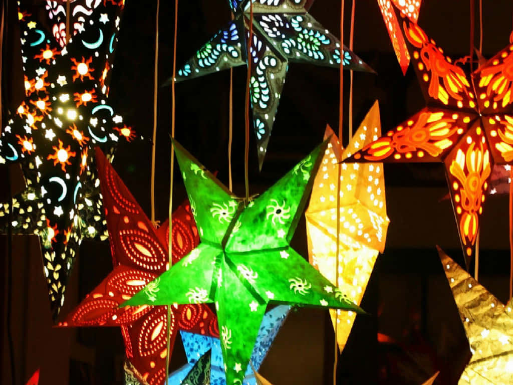 Christmas Star 桌布 壁紙 — 色彩繽紛的星形燈籠，帶有精緻的鏤空圖案，在黑暗背景下溫暖地發光。