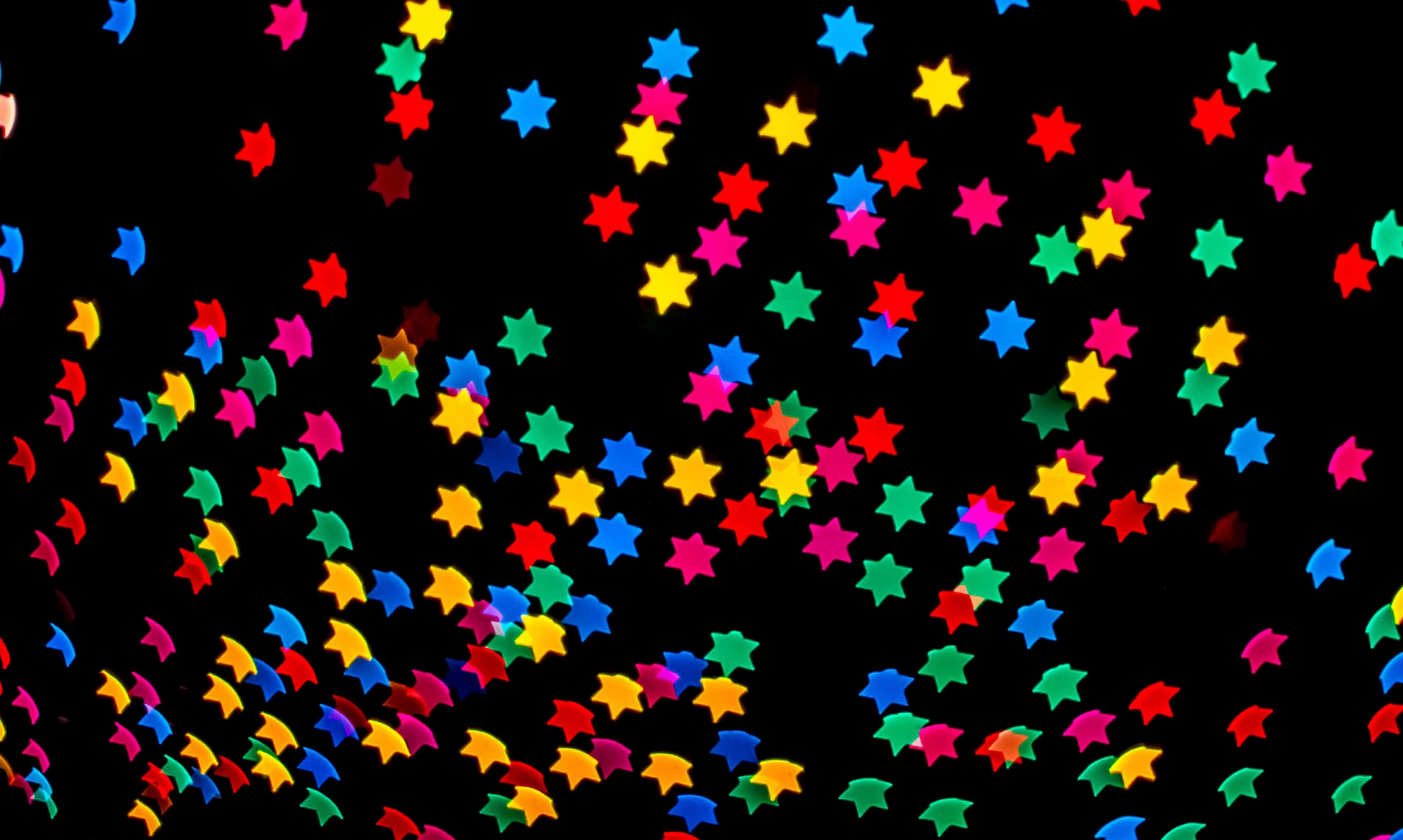 Stars 桌布 壁紙 — 色彩繽紛的星形紙屑在純黑背景上對角爆開。