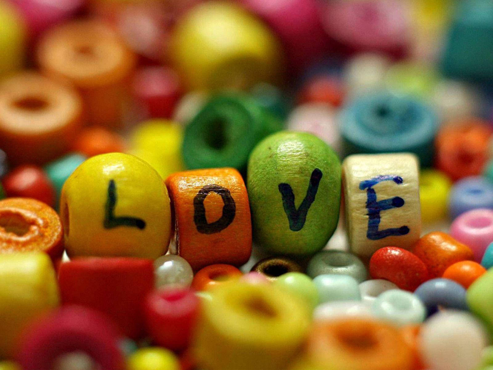 可愛的愛情 桌布 壁紙 — 色彩繽紛的木珠拼出 LOVE 的生動特寫，周圍是模糊的多色珠子。