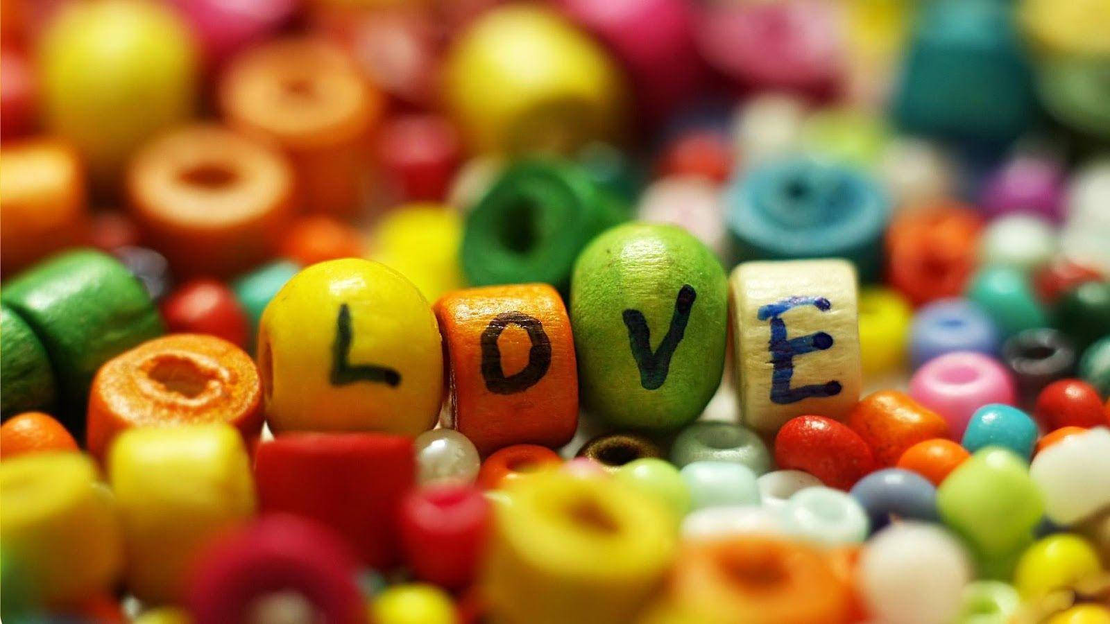 love full HD 桌布 壁紙 — 色彩繽紛的木珠拼出LOVE，以淺景深呈現，背景是各種珠子的彩虹模糊效果。